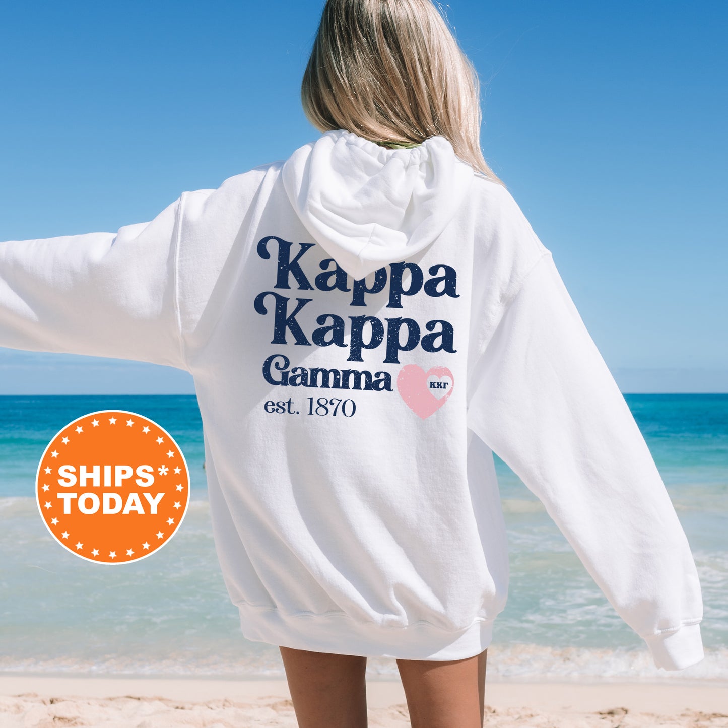 a woman standing on a beach wearing a white hoodie