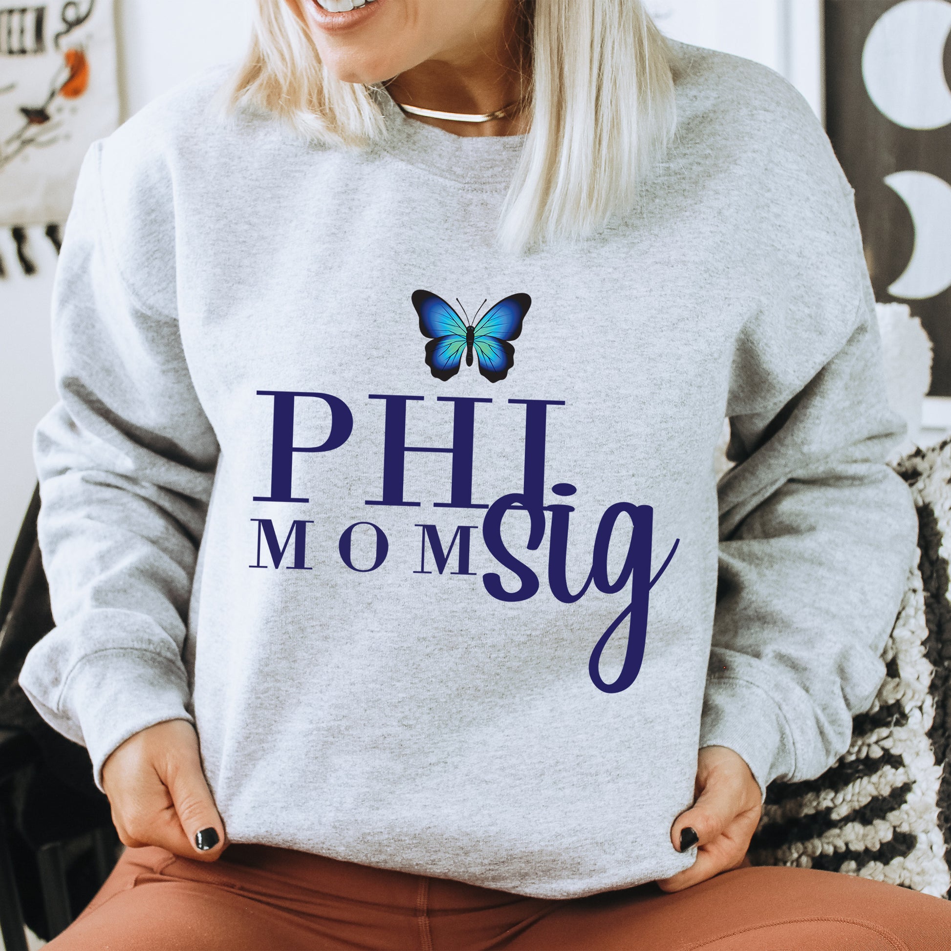 a woman sitting on a chair wearing a sweatshirt with a butterfly on it