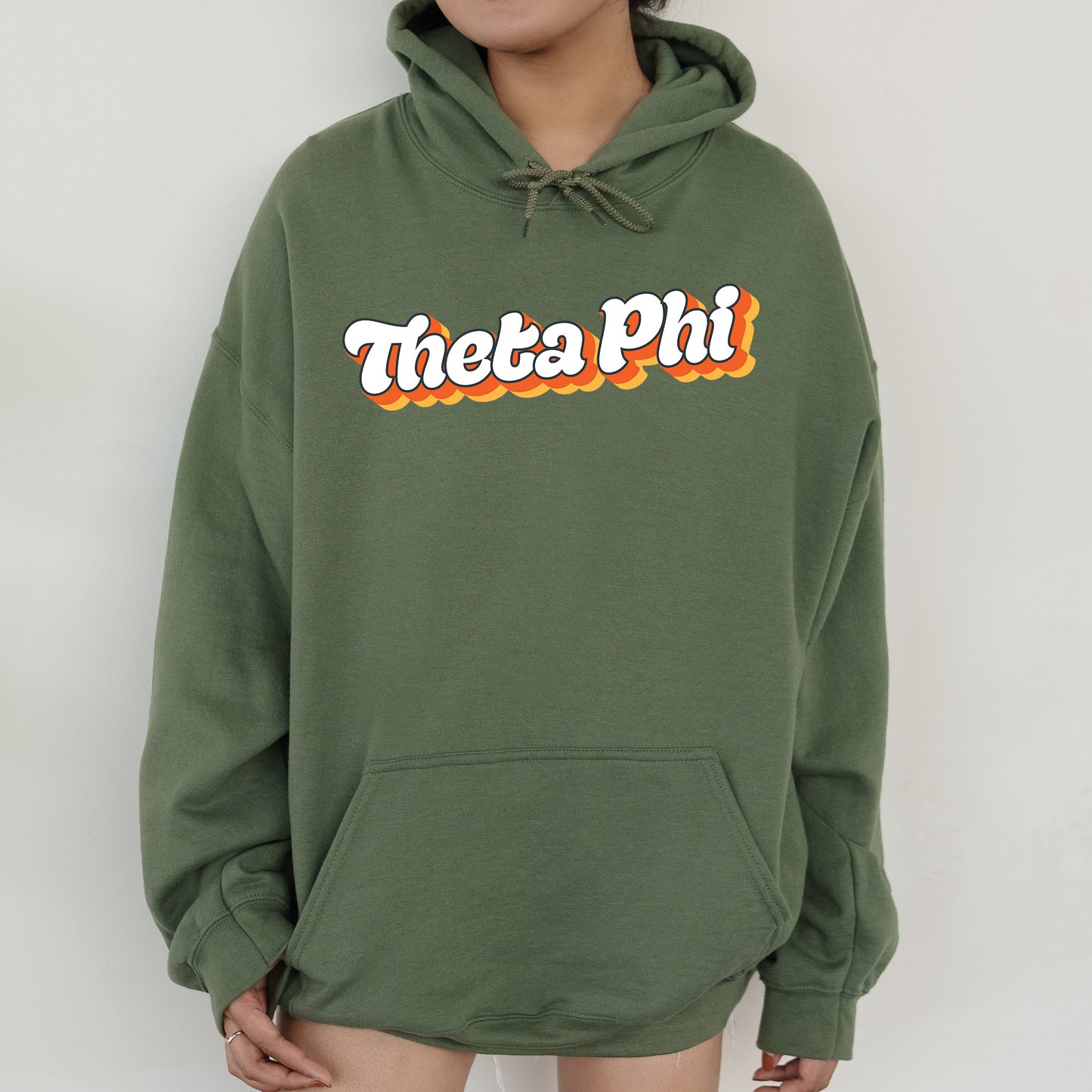 a person wearing a green hoodie with the words thea phi on it