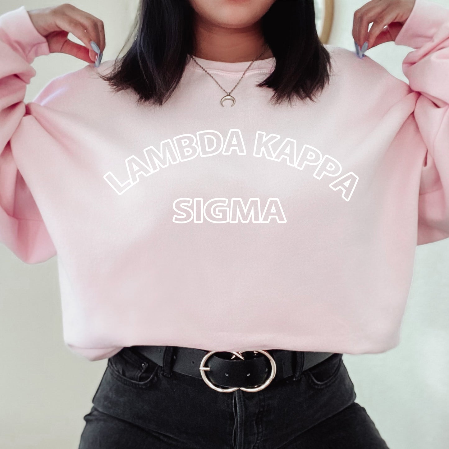 a woman wearing a pink sweatshirt that says lambda kappa sigma