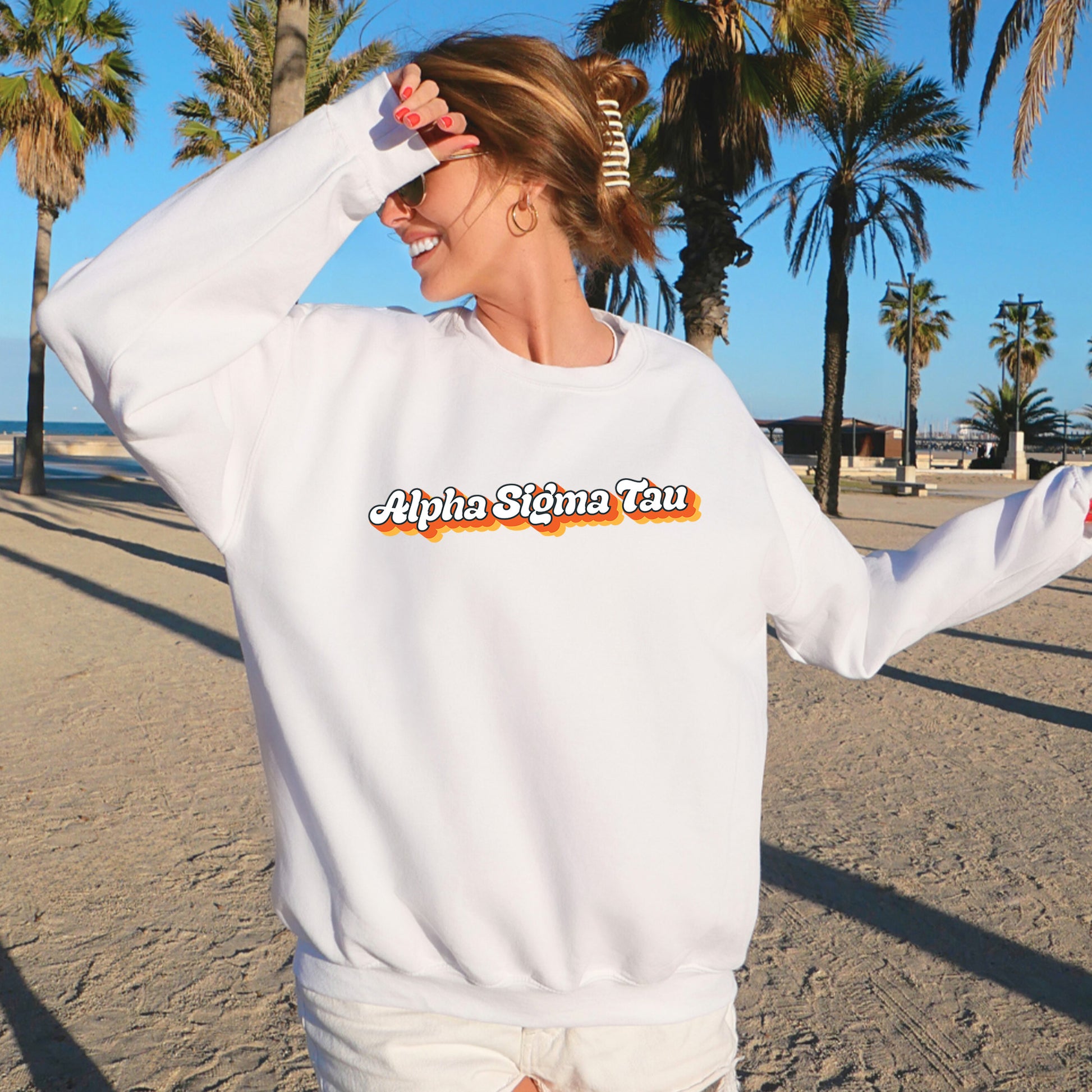 a woman standing on a beach wearing a white sweatshirt