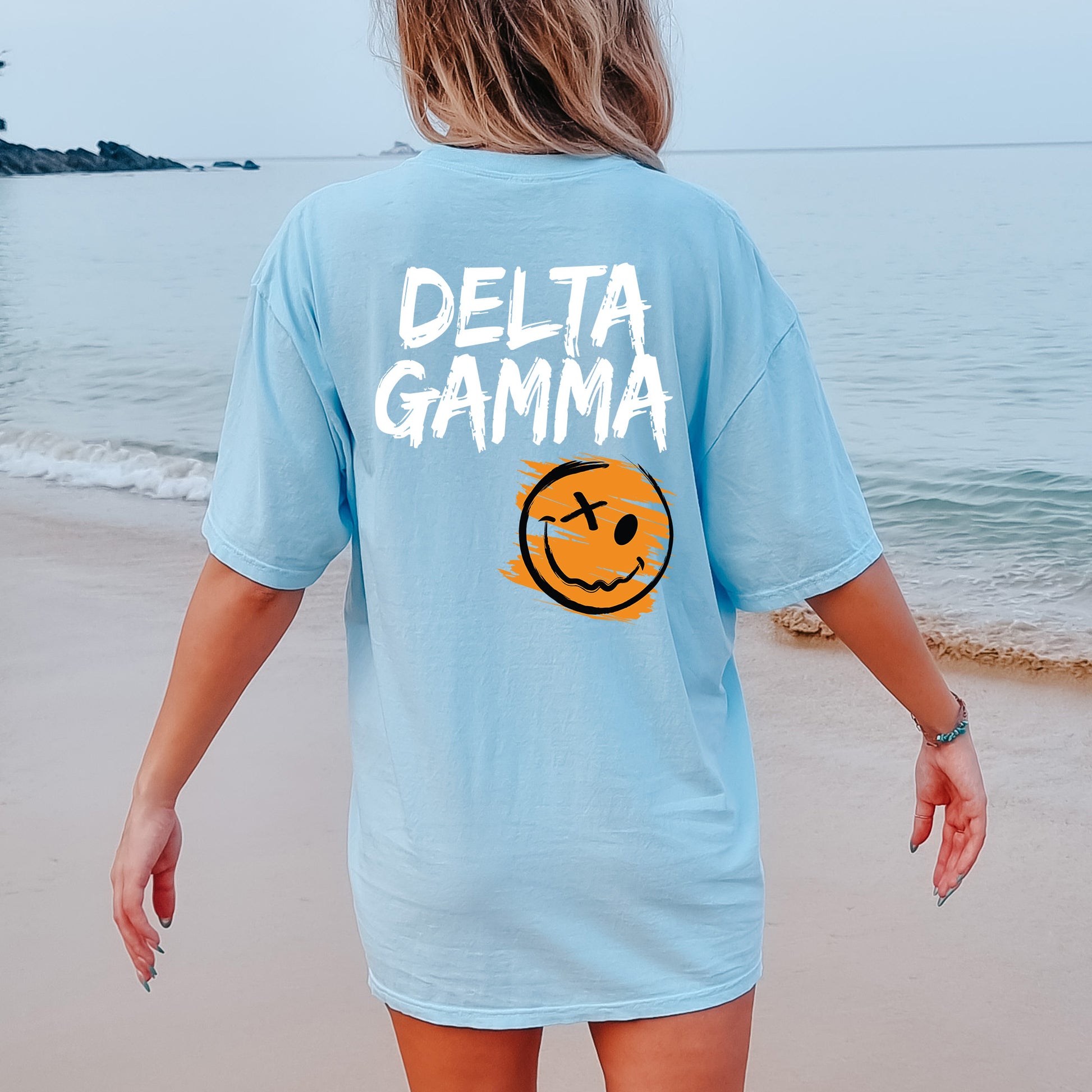 a woman walking on the beach with a smile on her shirt