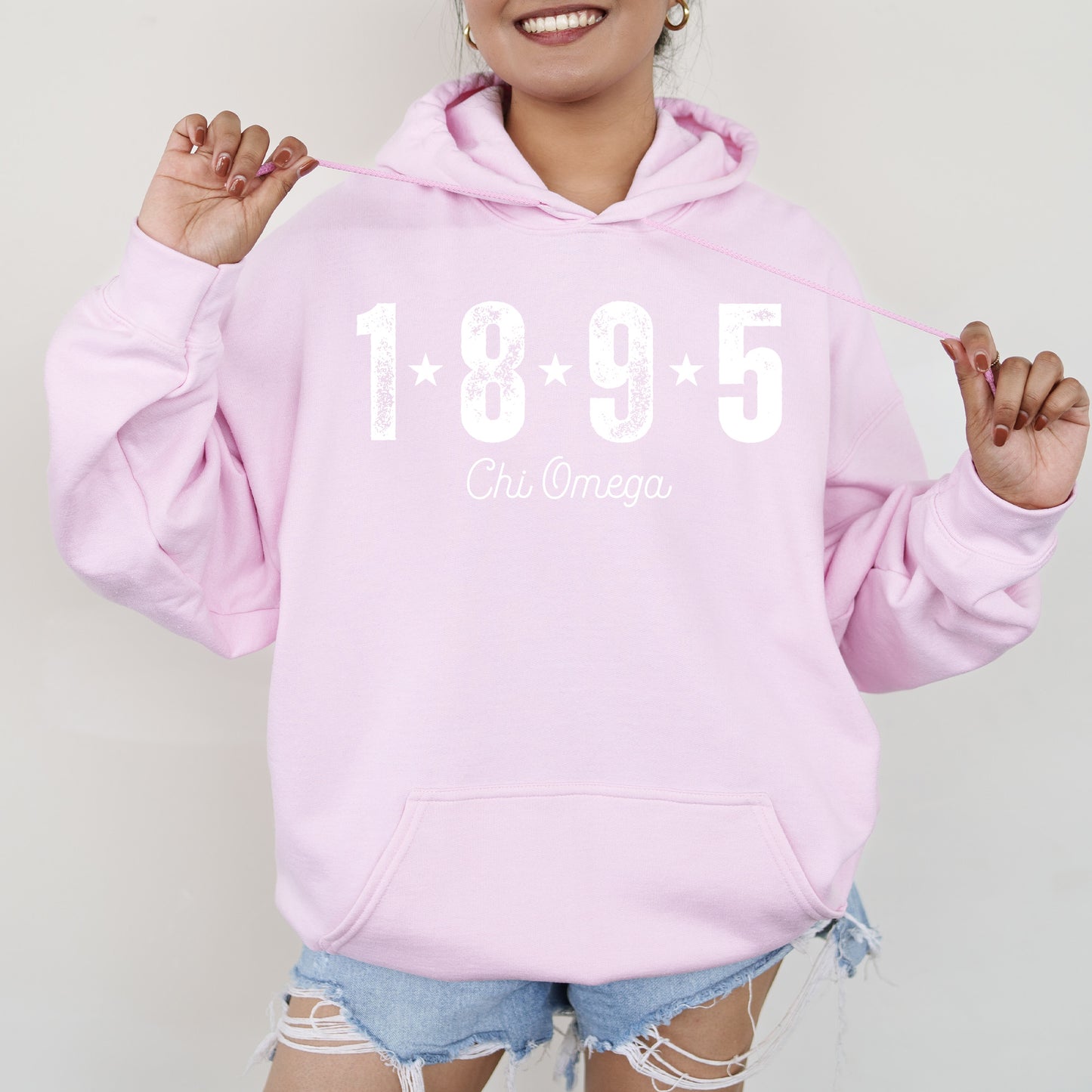 a woman wearing a pink hoodie and ripped shorts