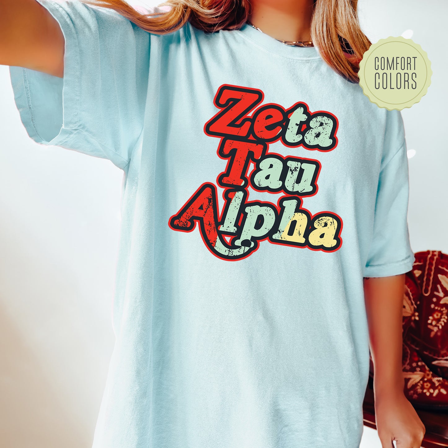 a woman wearing a light blue shirt with the words zeba tau alpha on