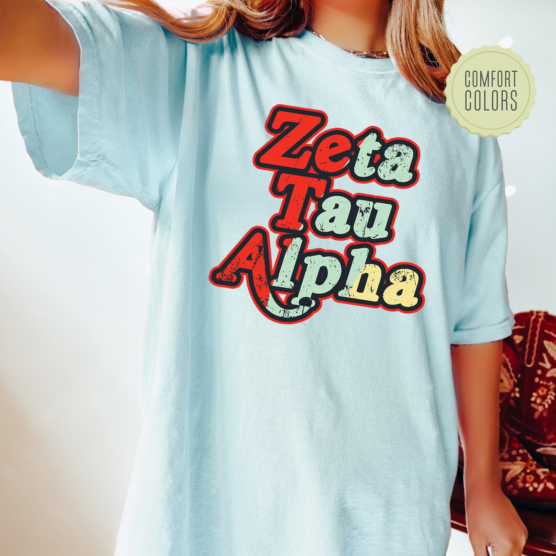 a woman wearing a light blue shirt with the words zeba tau alpha on