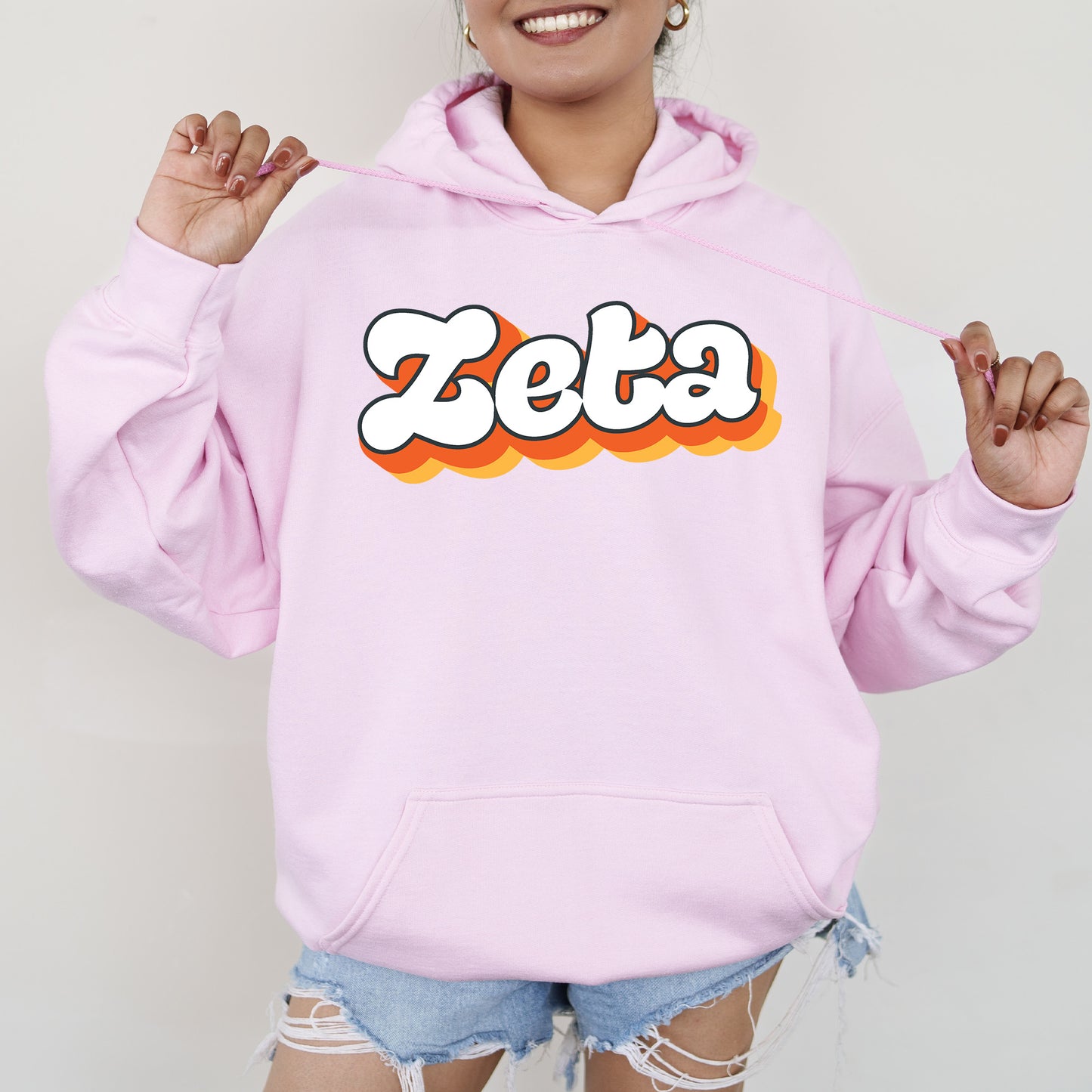 a woman wearing a pink hoodie with the word zeba on it