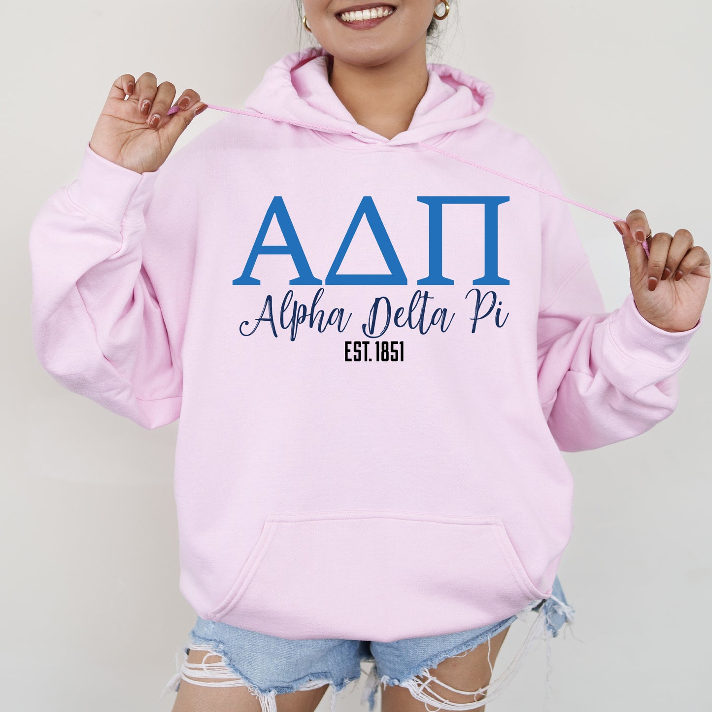 a woman wearing a pink hoodie with the letters delta on it