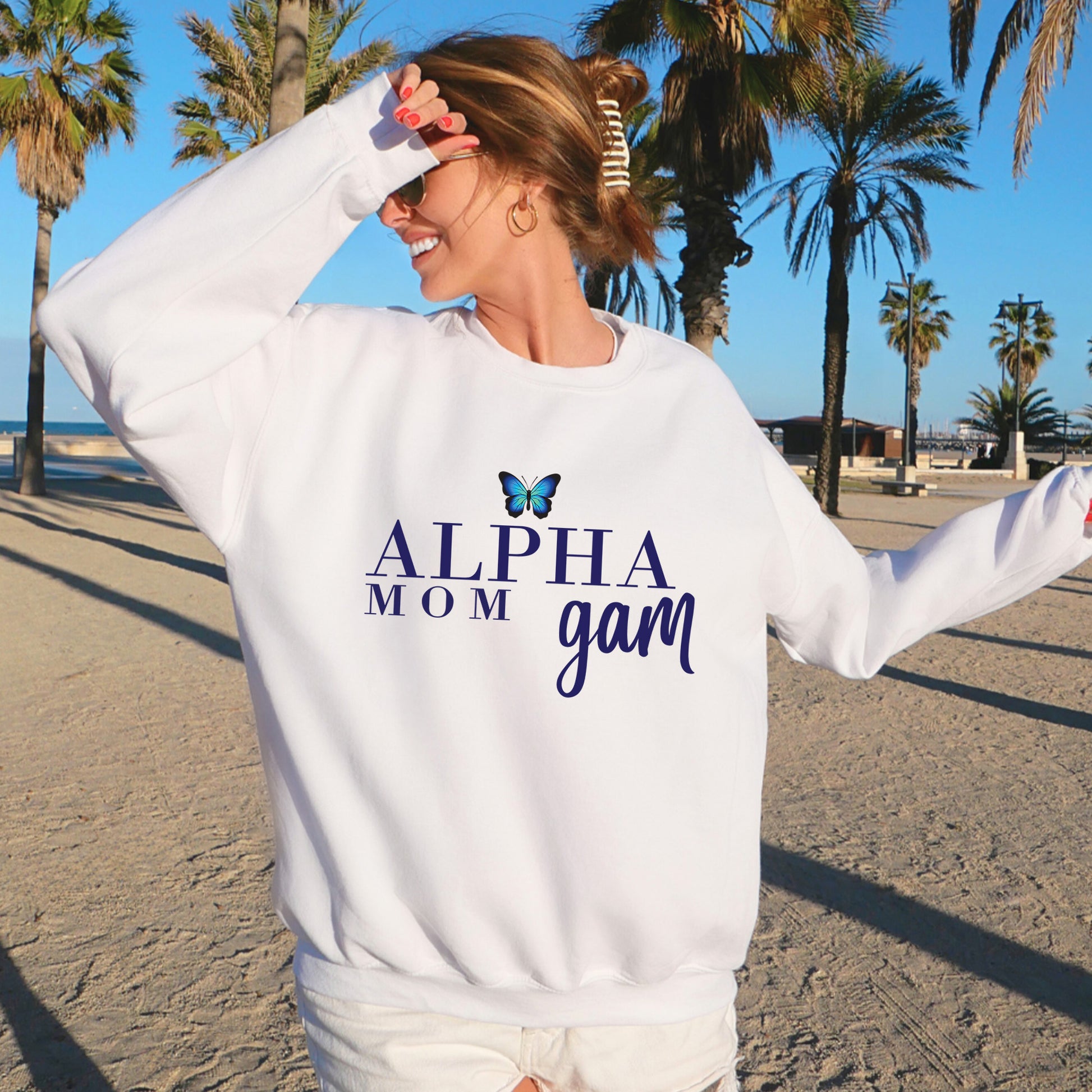 a woman standing on a beach wearing a white sweatshirt