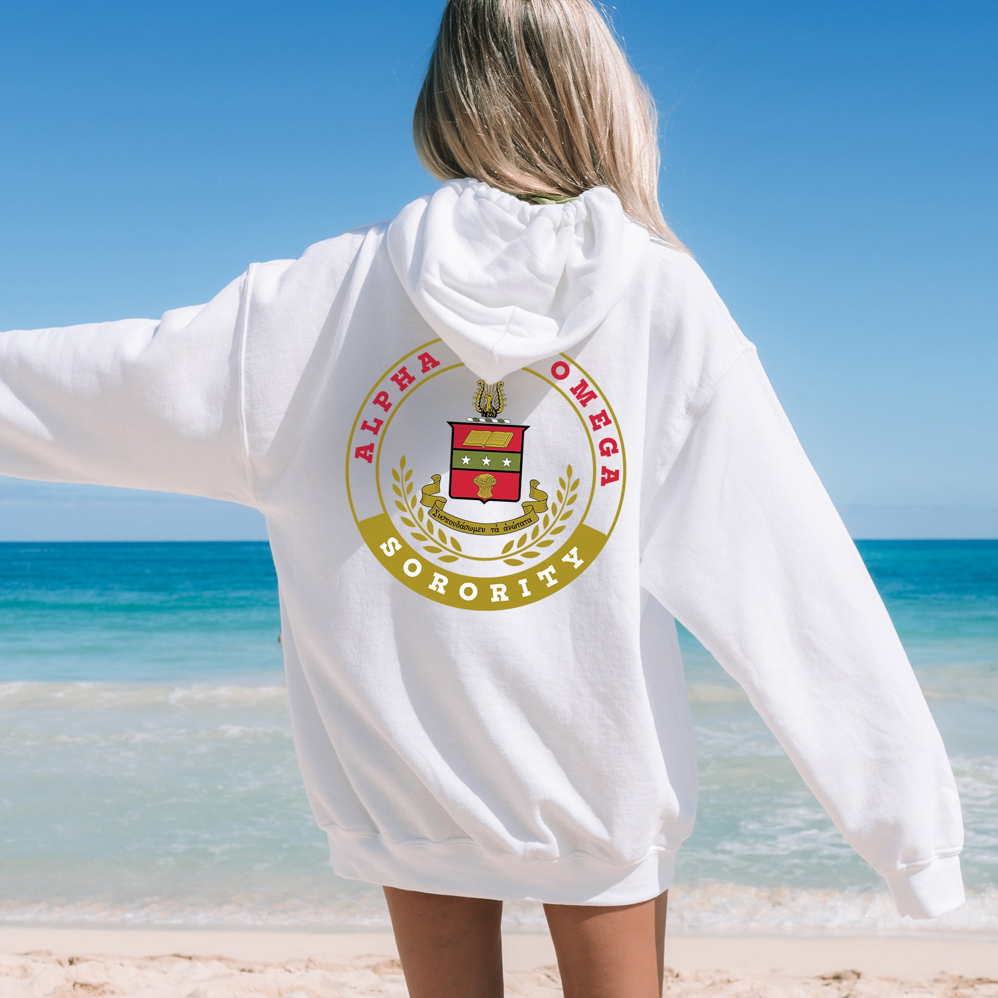 a woman standing on a beach wearing a white hoodie