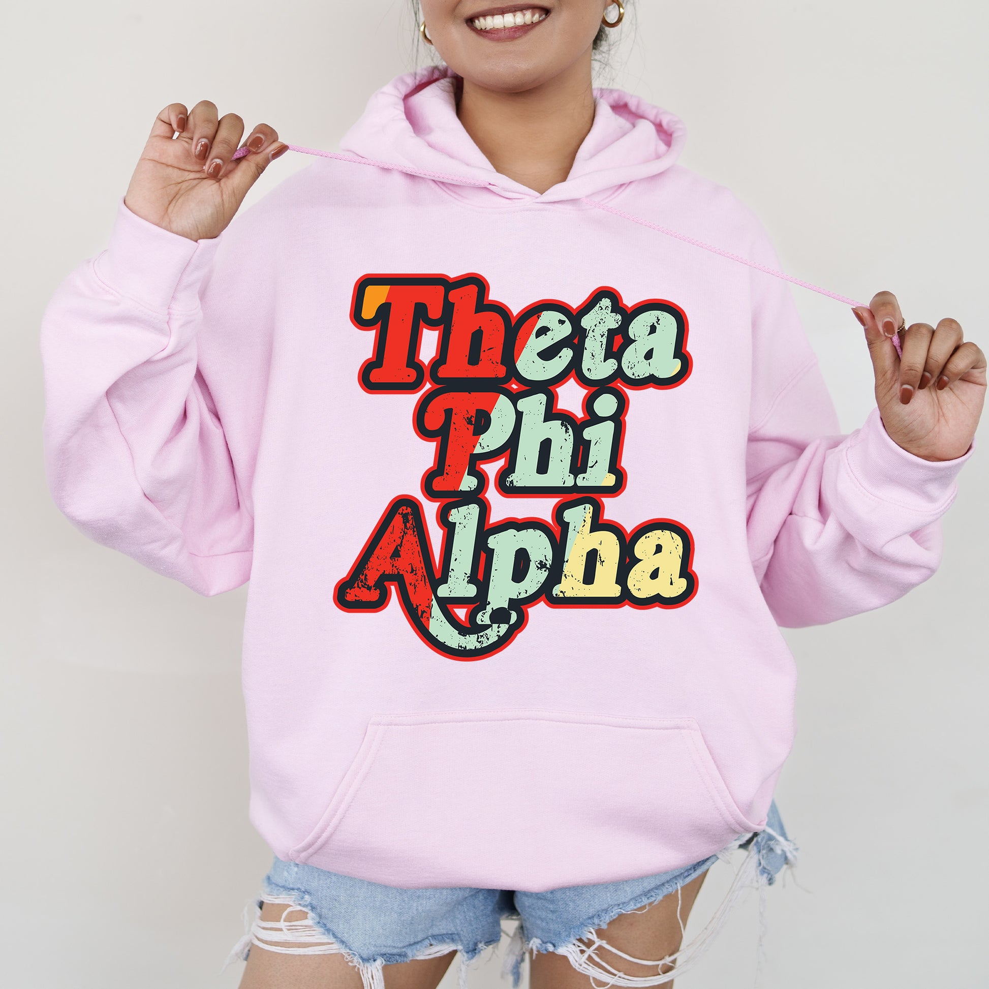 a woman wearing a pink hoodie that says thea phi phi aha