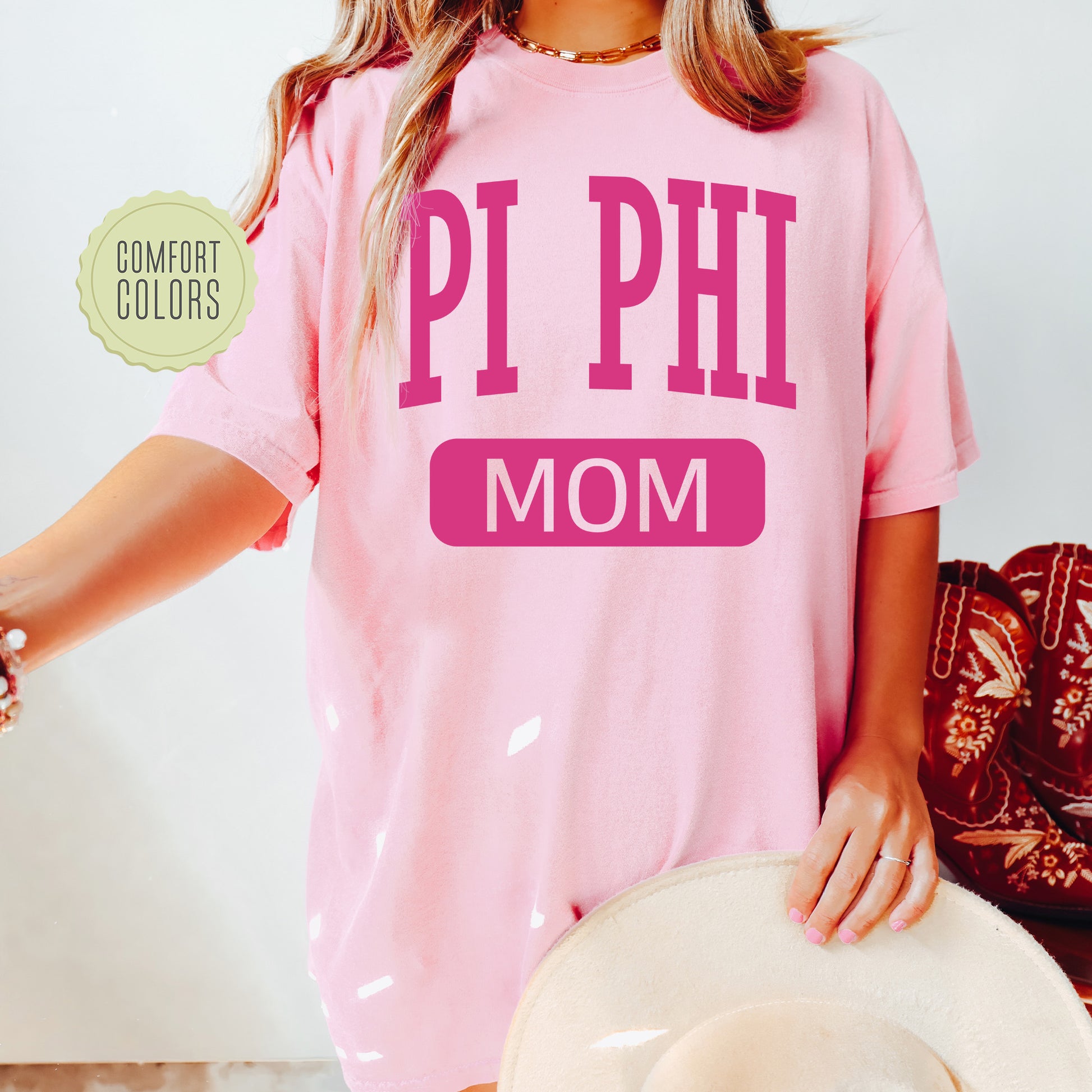 a woman wearing a pink shirt that says pi phi mom