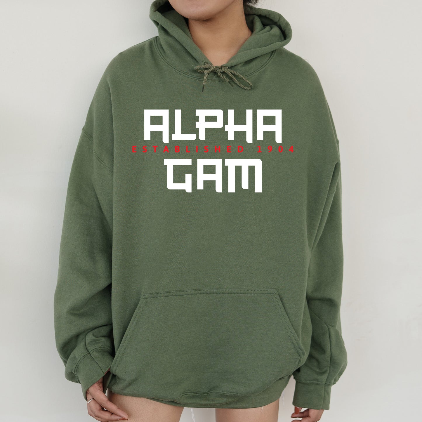 a person wearing a green hoodie with the words alpha gam on it