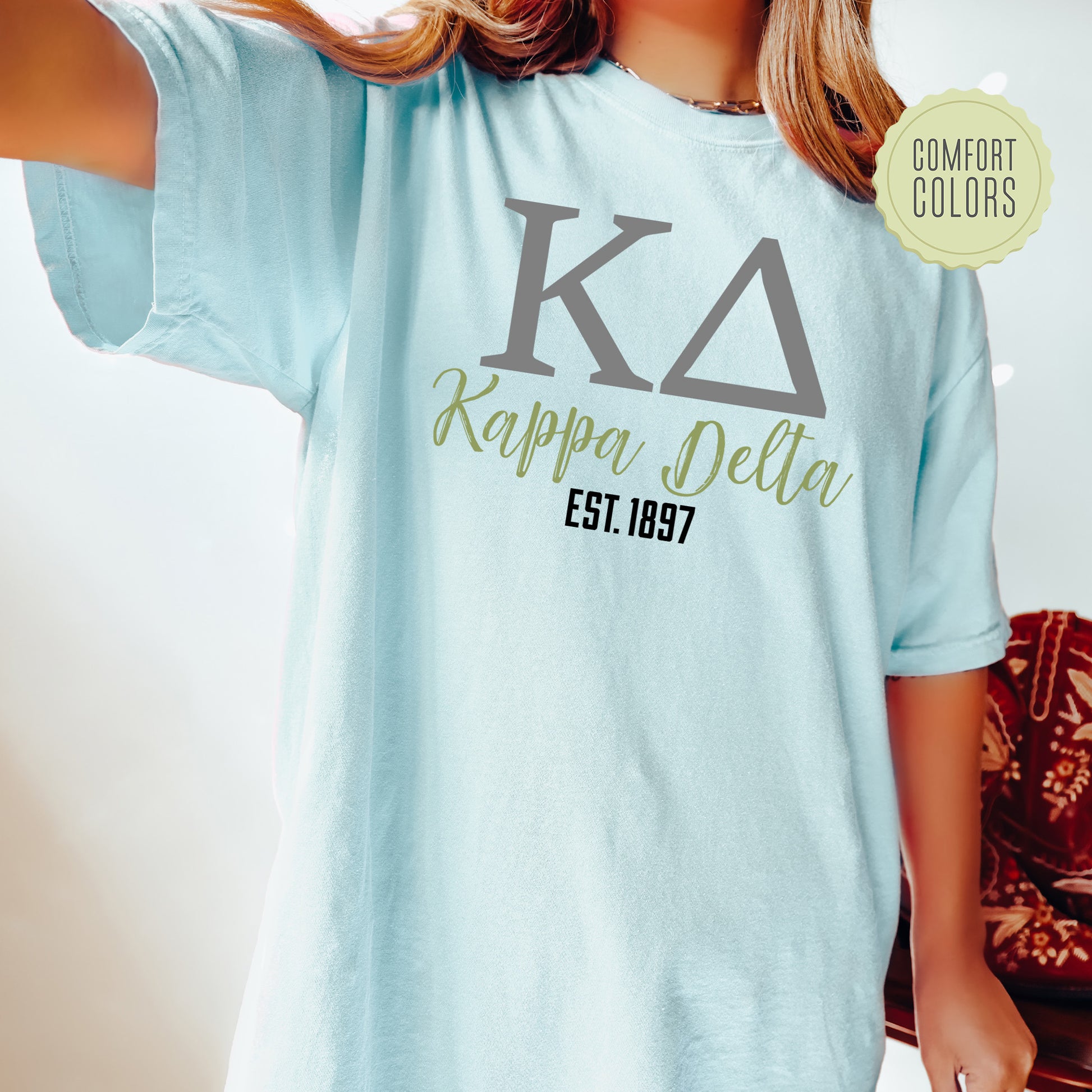 a woman wearing a light blue shirt with the letters karppaa delta on