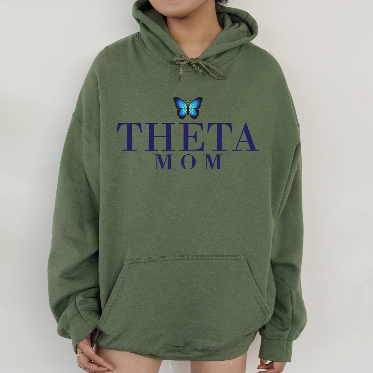 a woman wearing a sweatshirt with the words thea mom on it