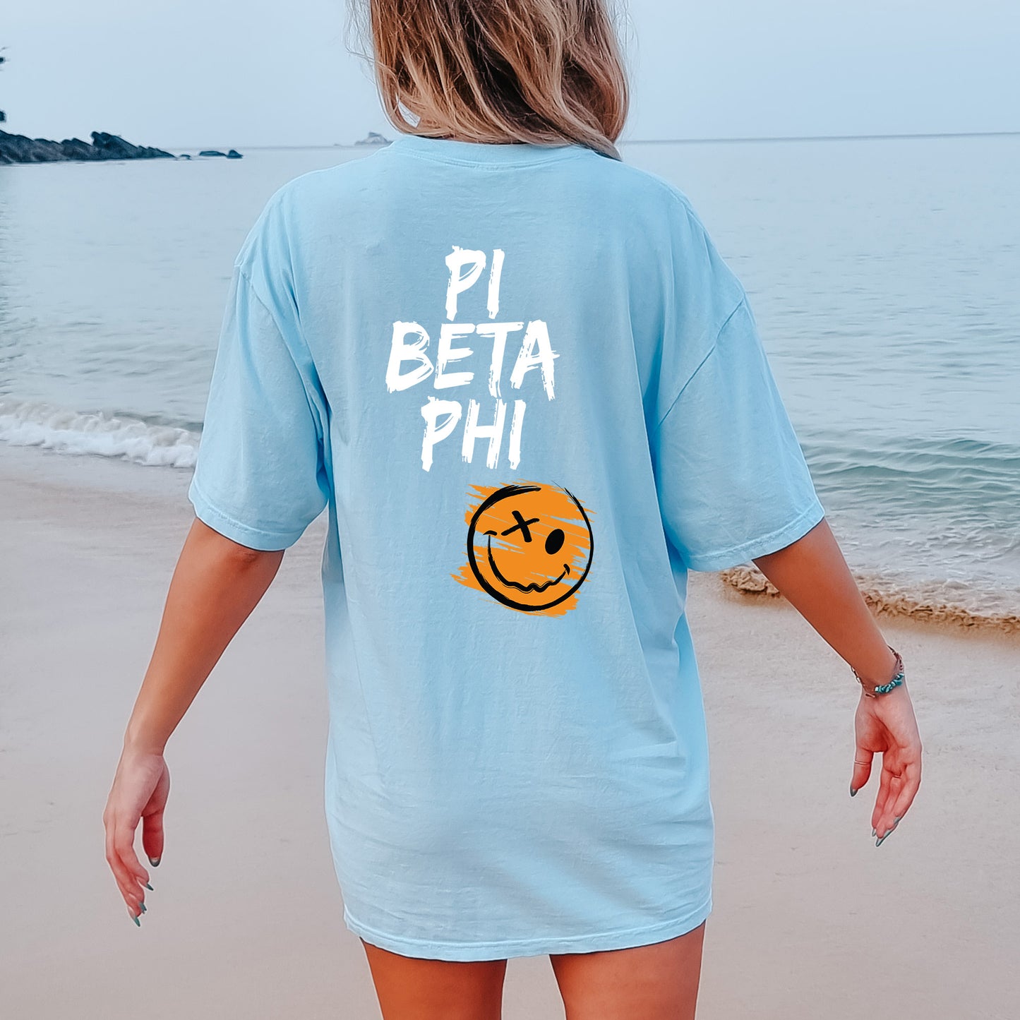 a woman walking on the beach with a smile on her shirt