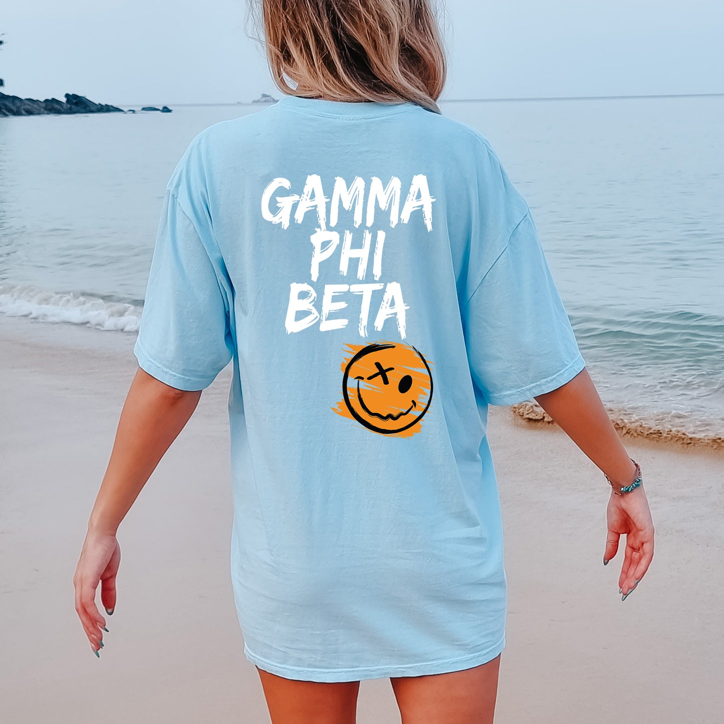 a woman walking on the beach with a smile on her shirt
