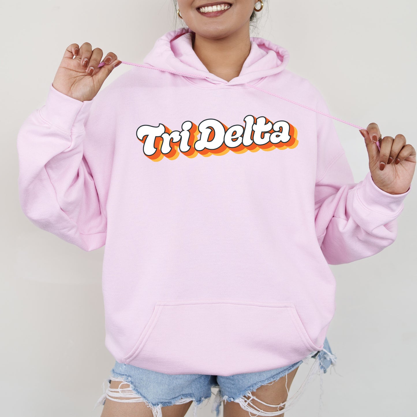 a woman wearing a pink hoodie with the word tri delta on it