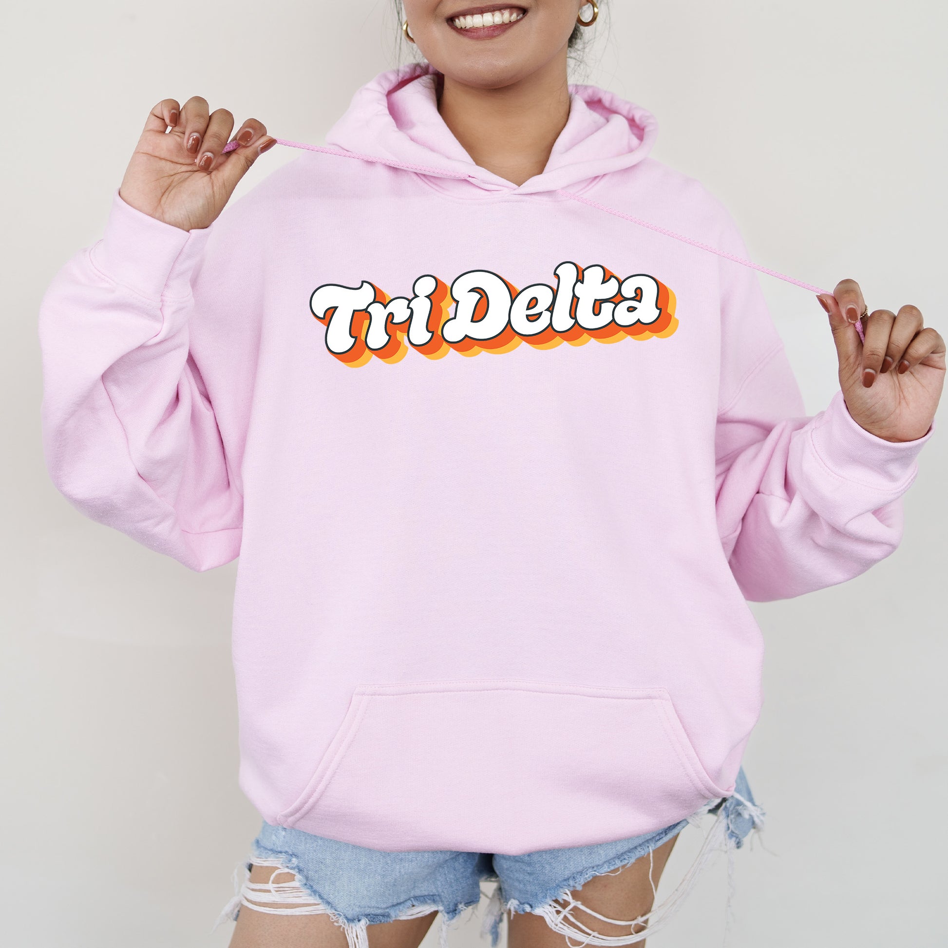 a woman wearing a pink hoodie with the word tri delta on it