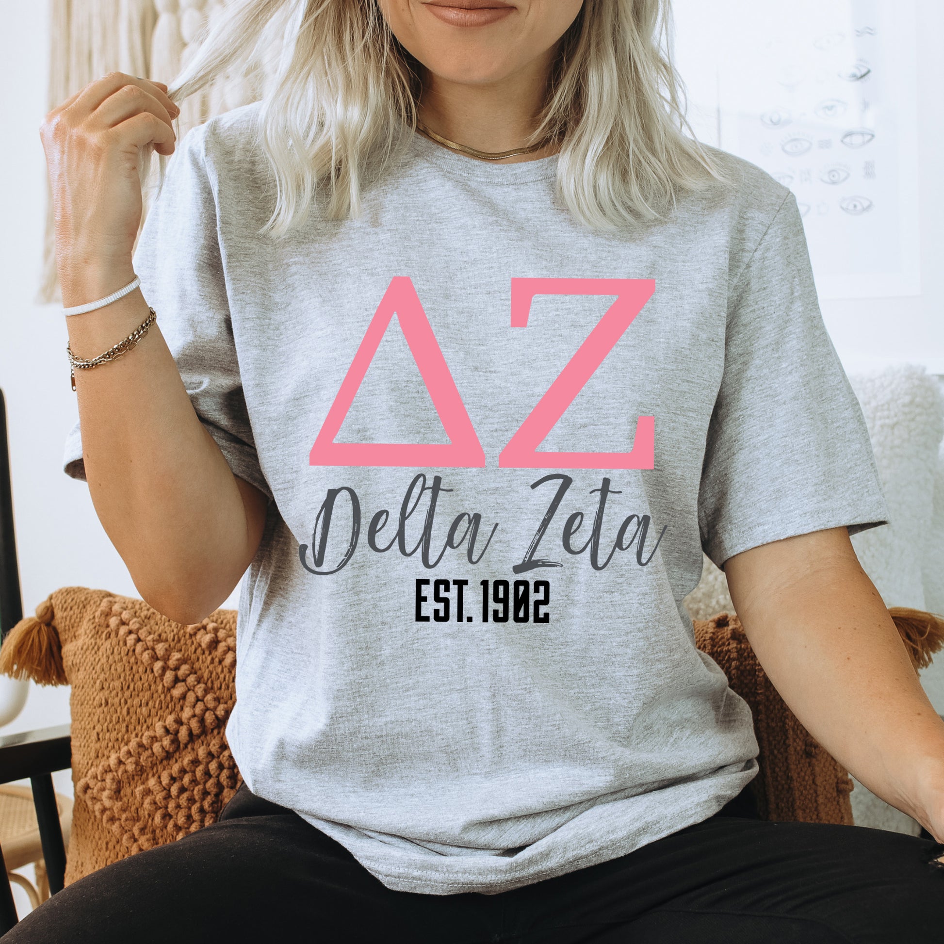 a woman sitting on a chair wearing a delta delta shirt