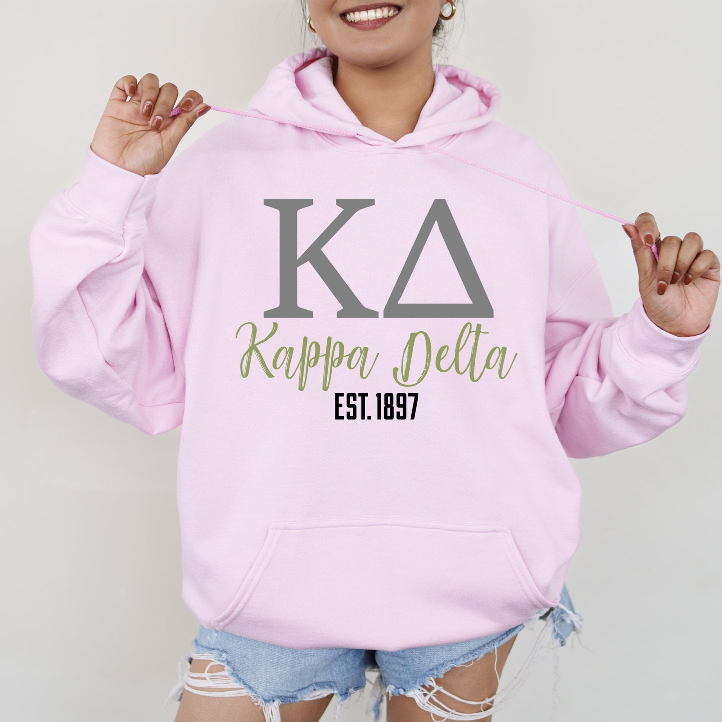 a woman wearing a pink hoodie with the letters kapppa pella on