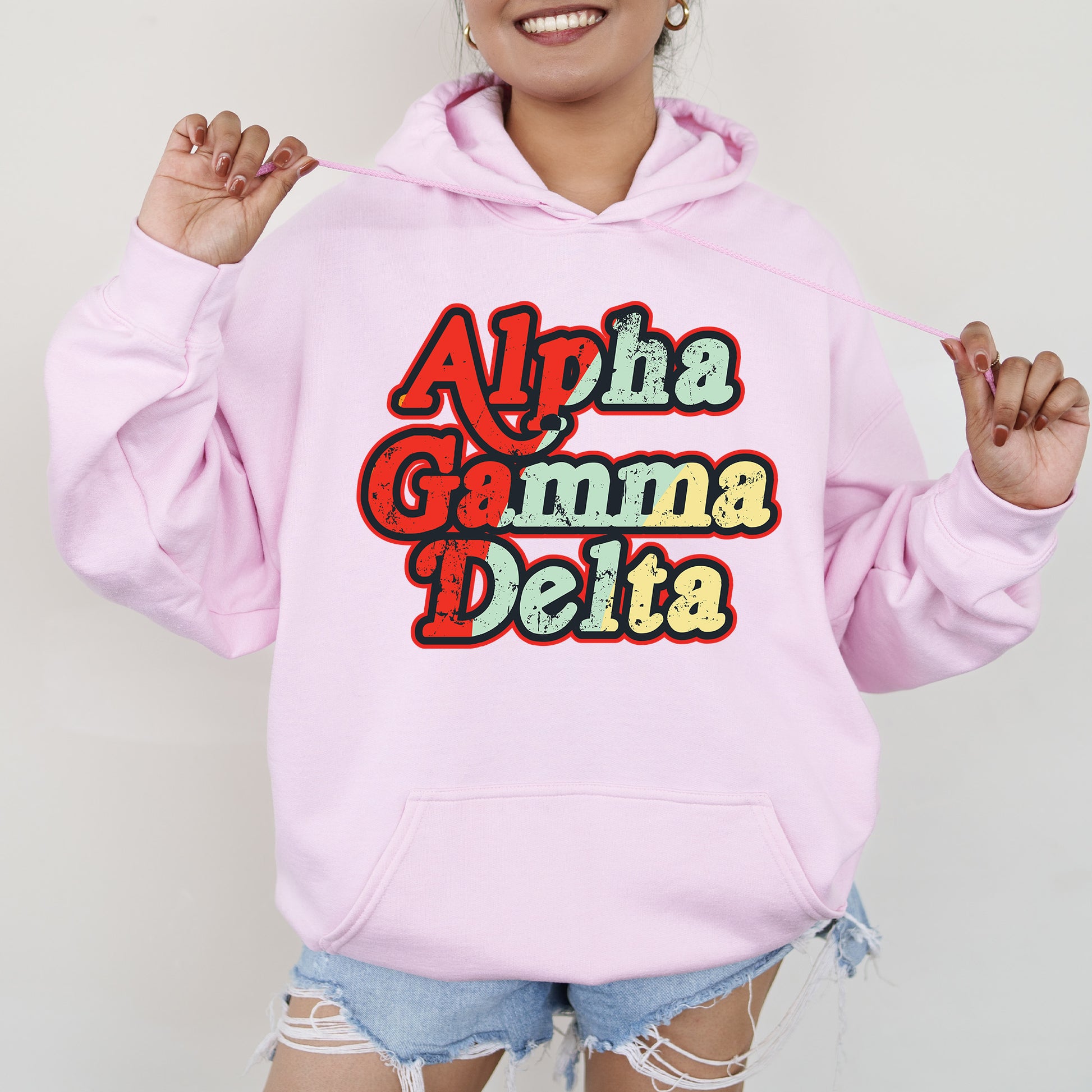 a woman wearing a pink hoodie with the words aloh gama delta on