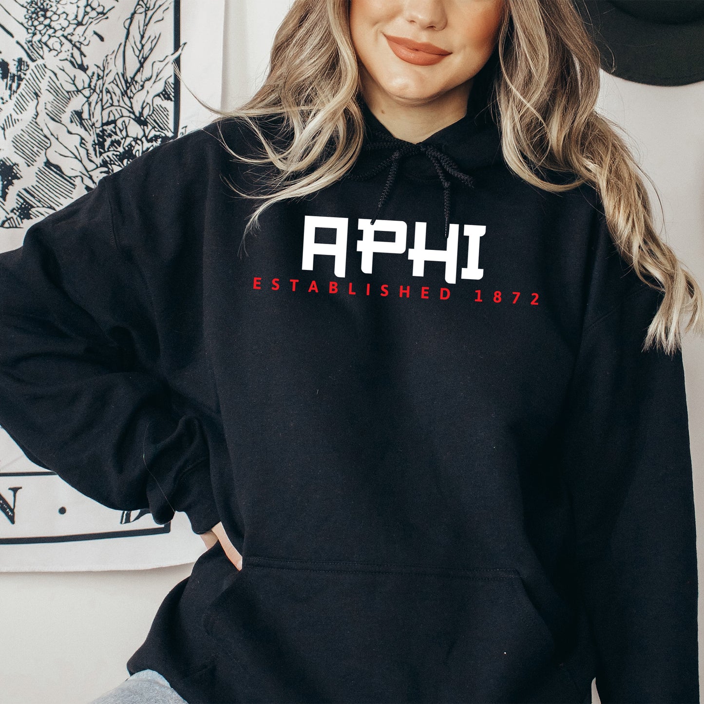 a woman wearing a black hoodie that says aphi established 1932