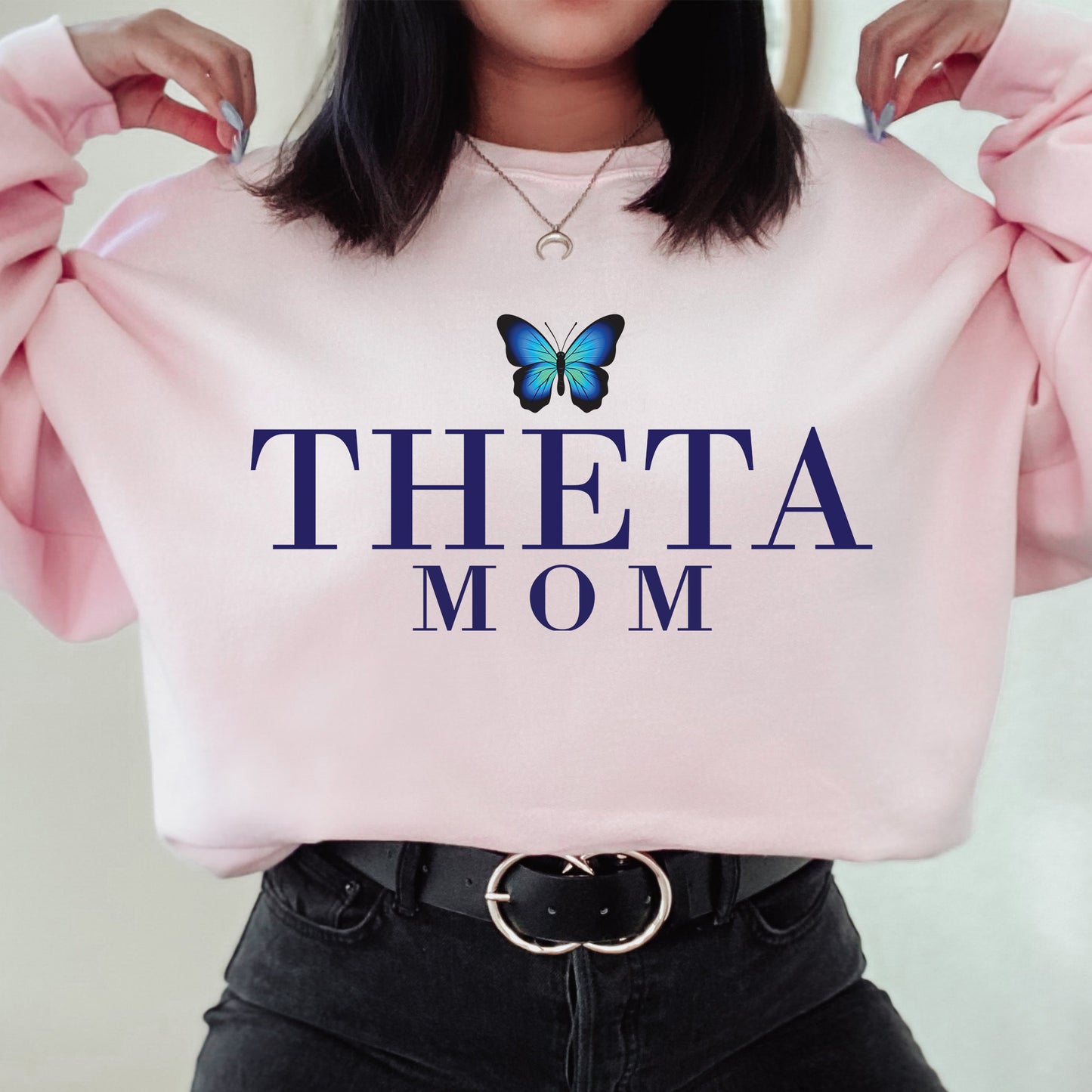 a woman holding a pink sweatshirt with a butterfly on it