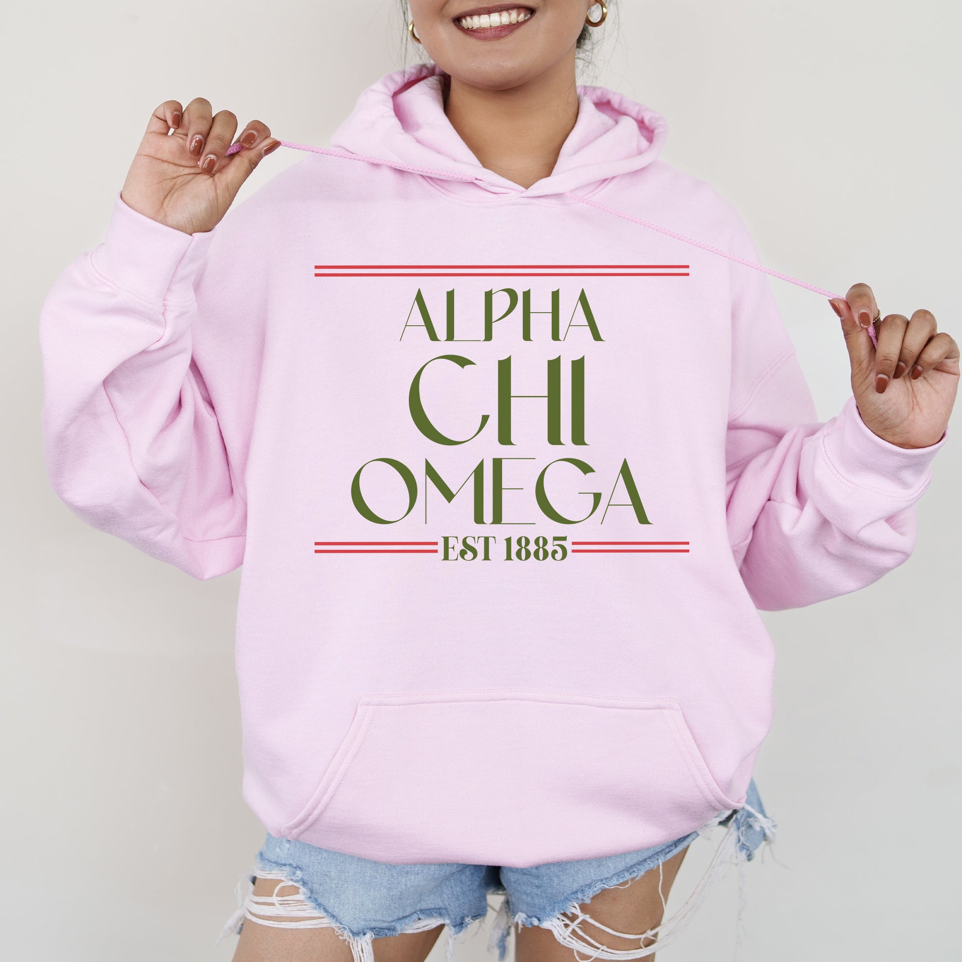 a woman wearing a pink hoodie with the words, alpha chi omega on it