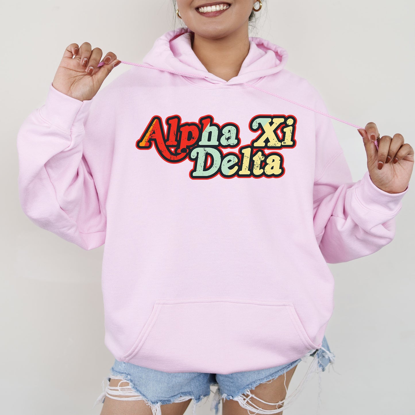 a woman wearing a pink hoodie that says aha xi delta