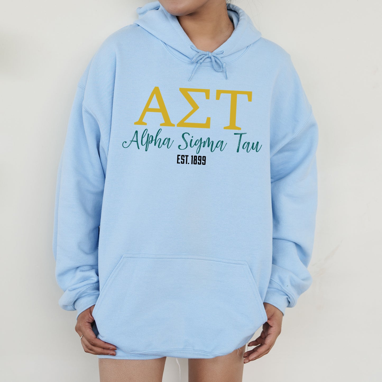 a person wearing a light blue hoodie with the letters a, t, and