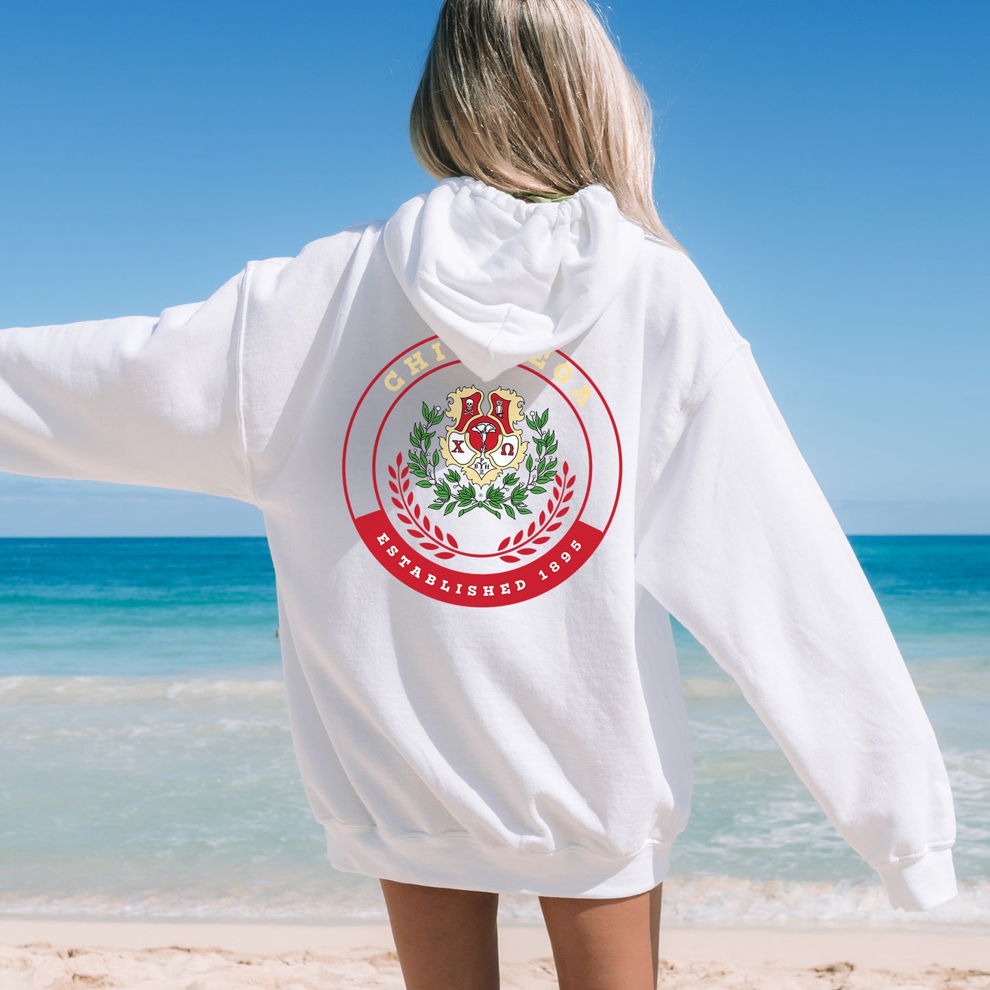 a woman standing on a beach wearing a white hoodie