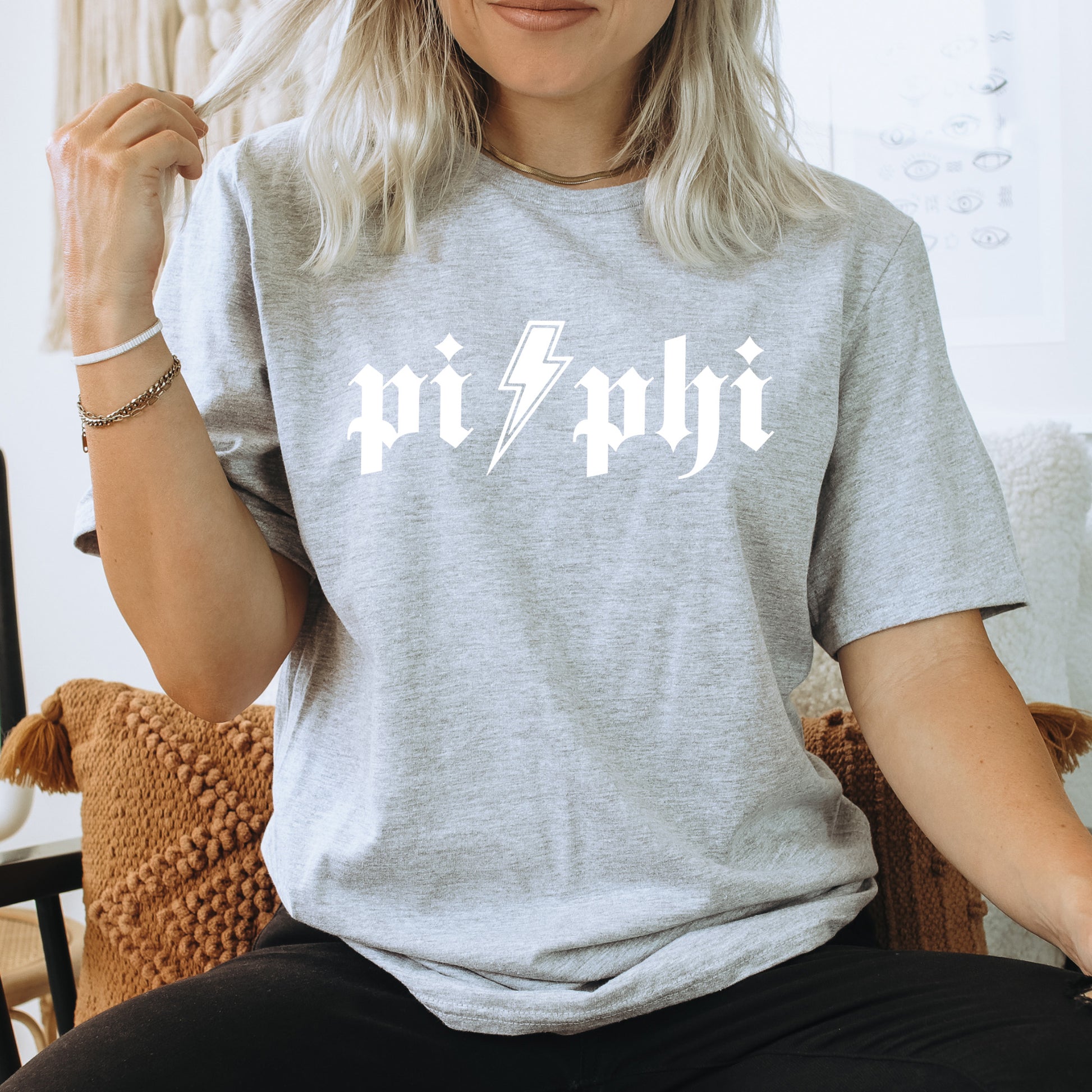 a woman sitting on a chair wearing a grey shirt with a lightning bolt on it