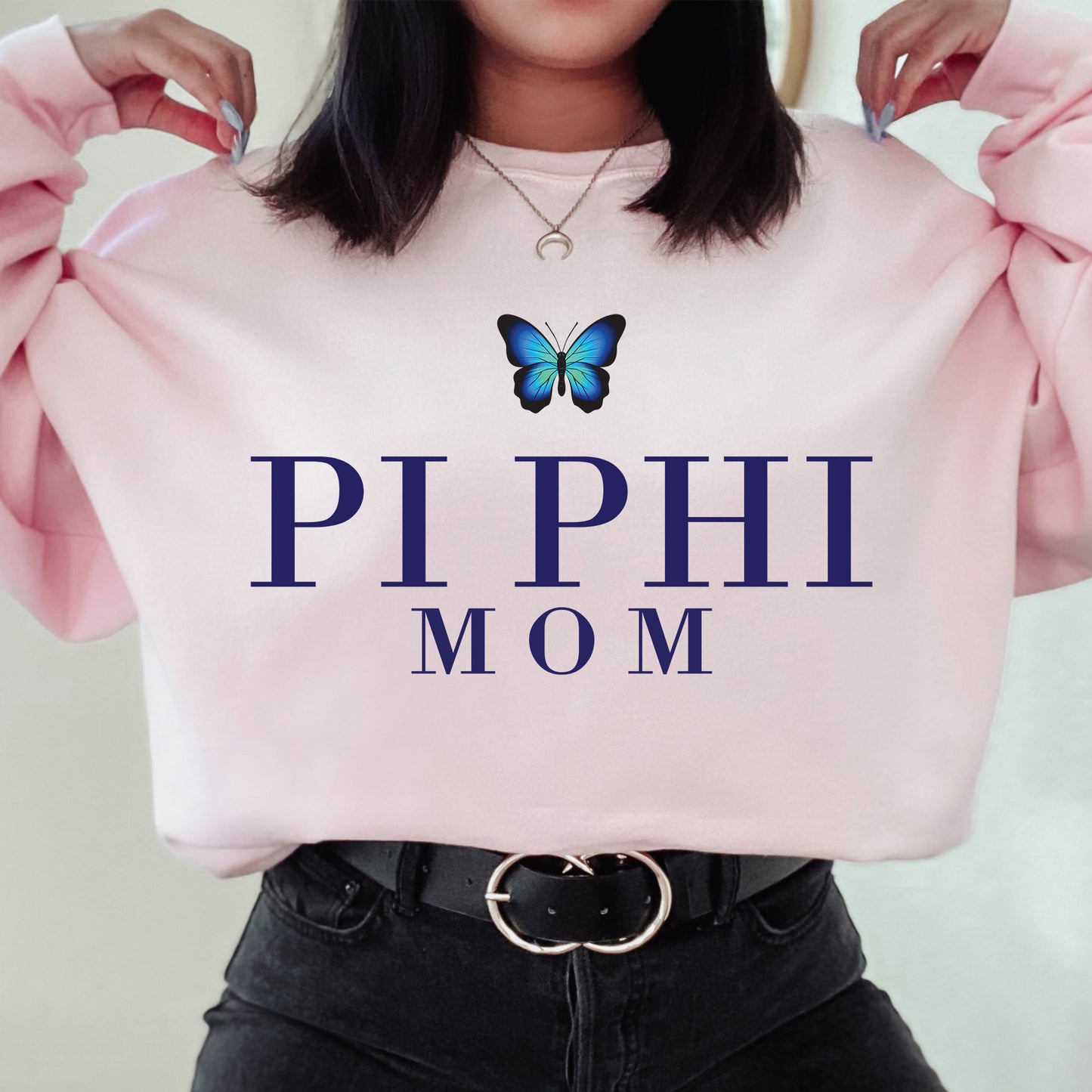 a woman holding a pink sweatshirt with a butterfly on it