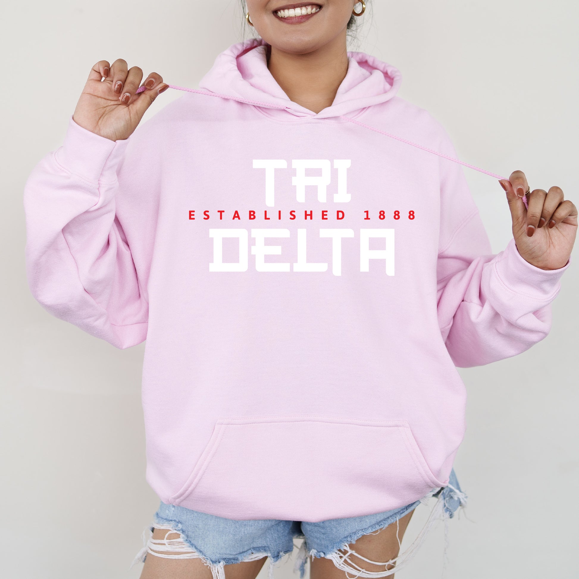 a woman wearing a pink hoodie that says established in both white and red letters
