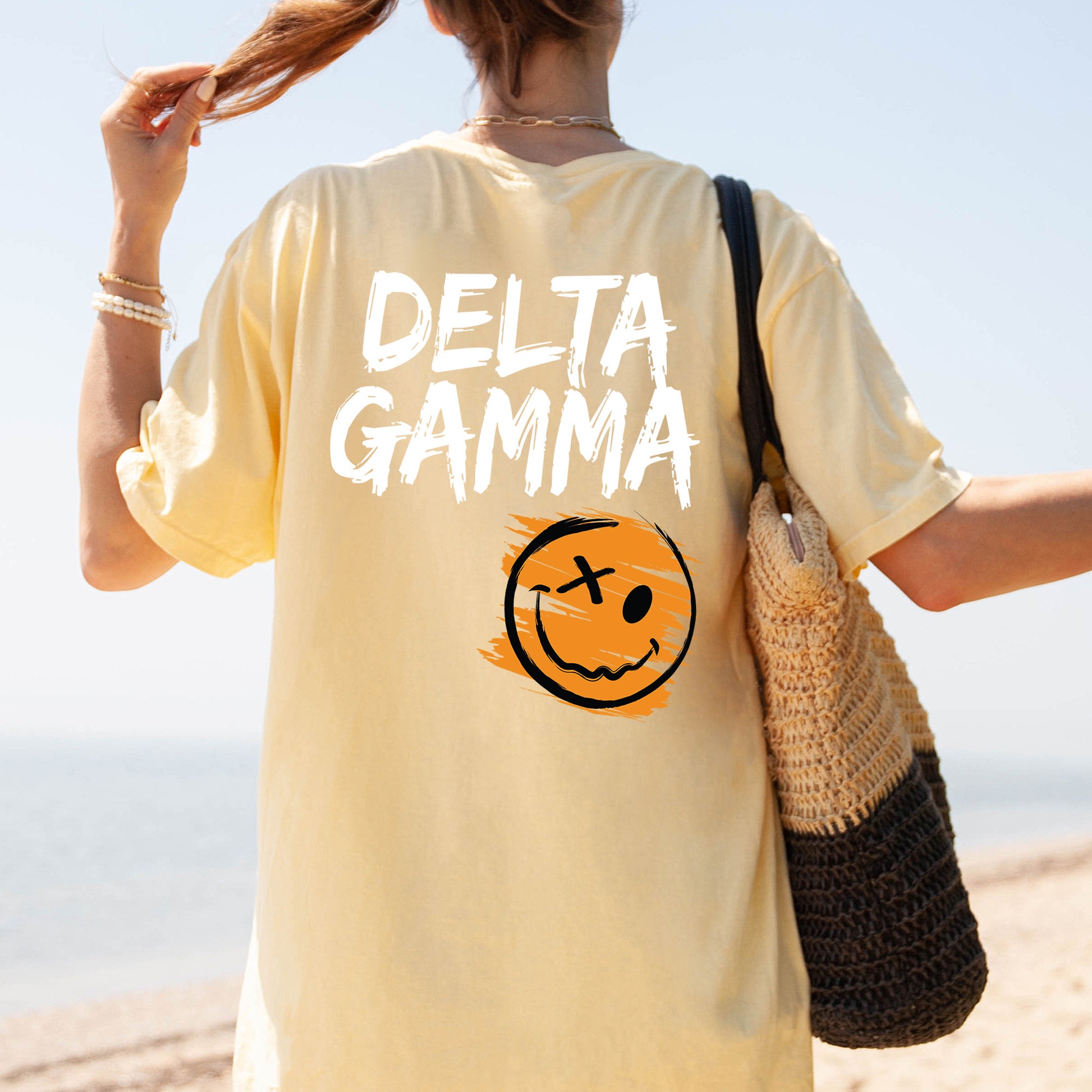 a woman walking on the beach with a smile on her shirt
