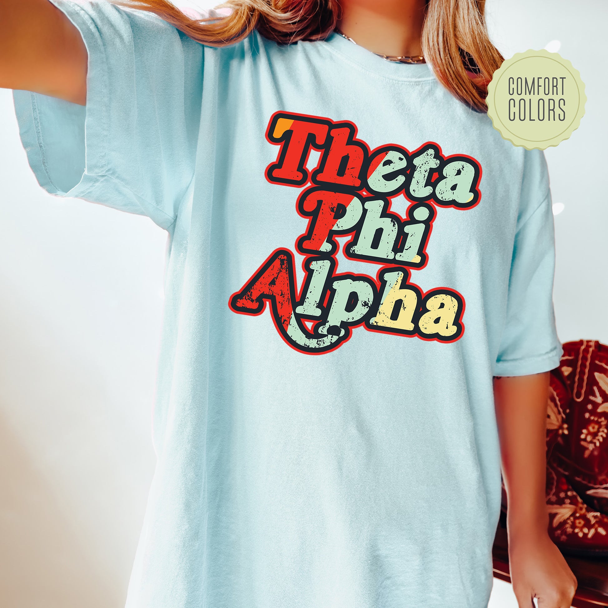 a woman wearing a blue shirt with the words thea phi aha on it