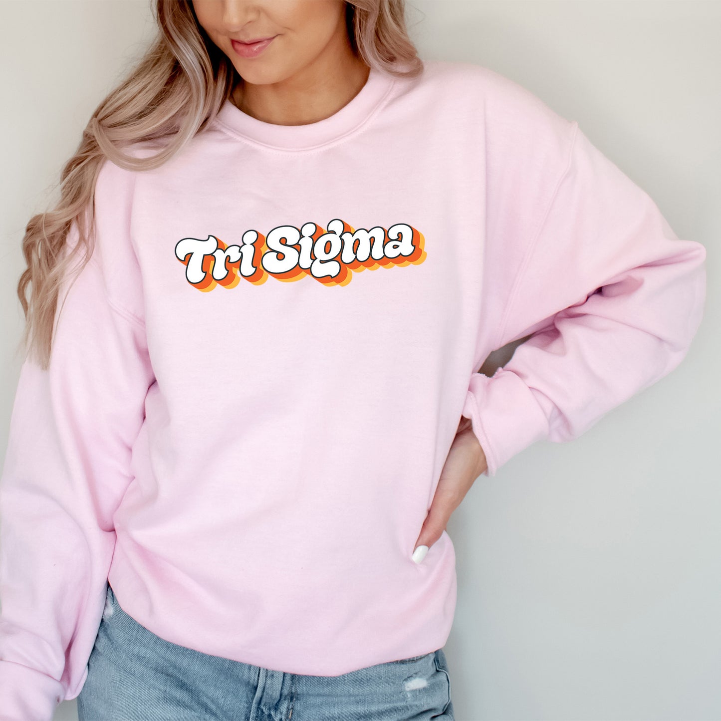 a woman wearing a pink sweatshirt with the word tri stigma on it