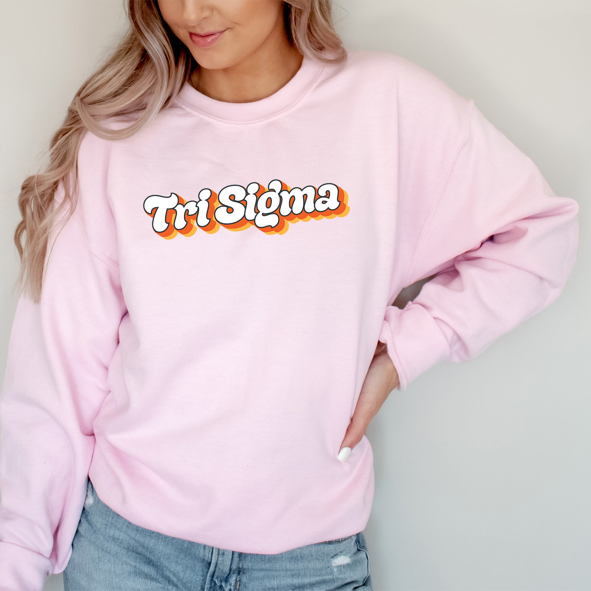 a woman wearing a pink sweatshirt with the word tri stigma on it