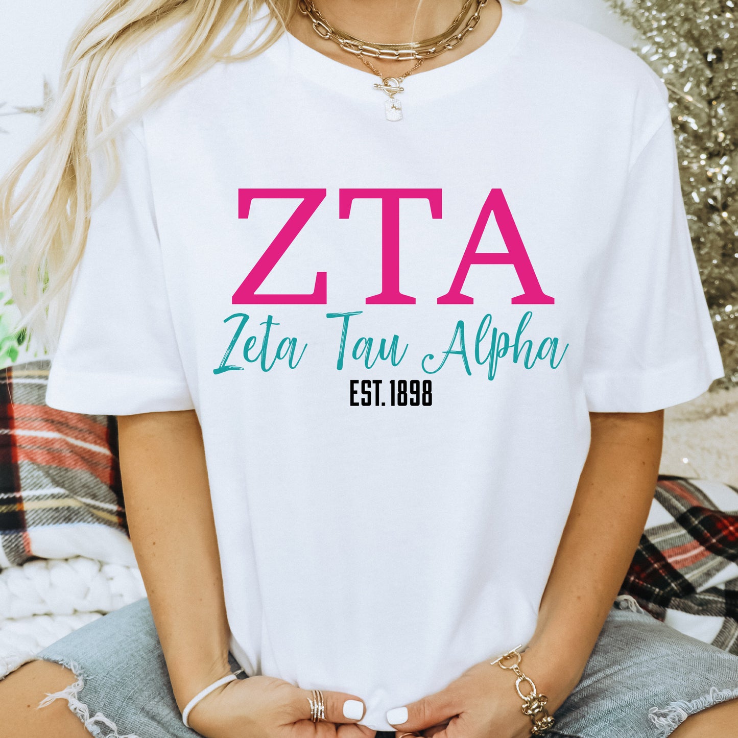 a woman wearing a white t - shirt with a pink zta on it