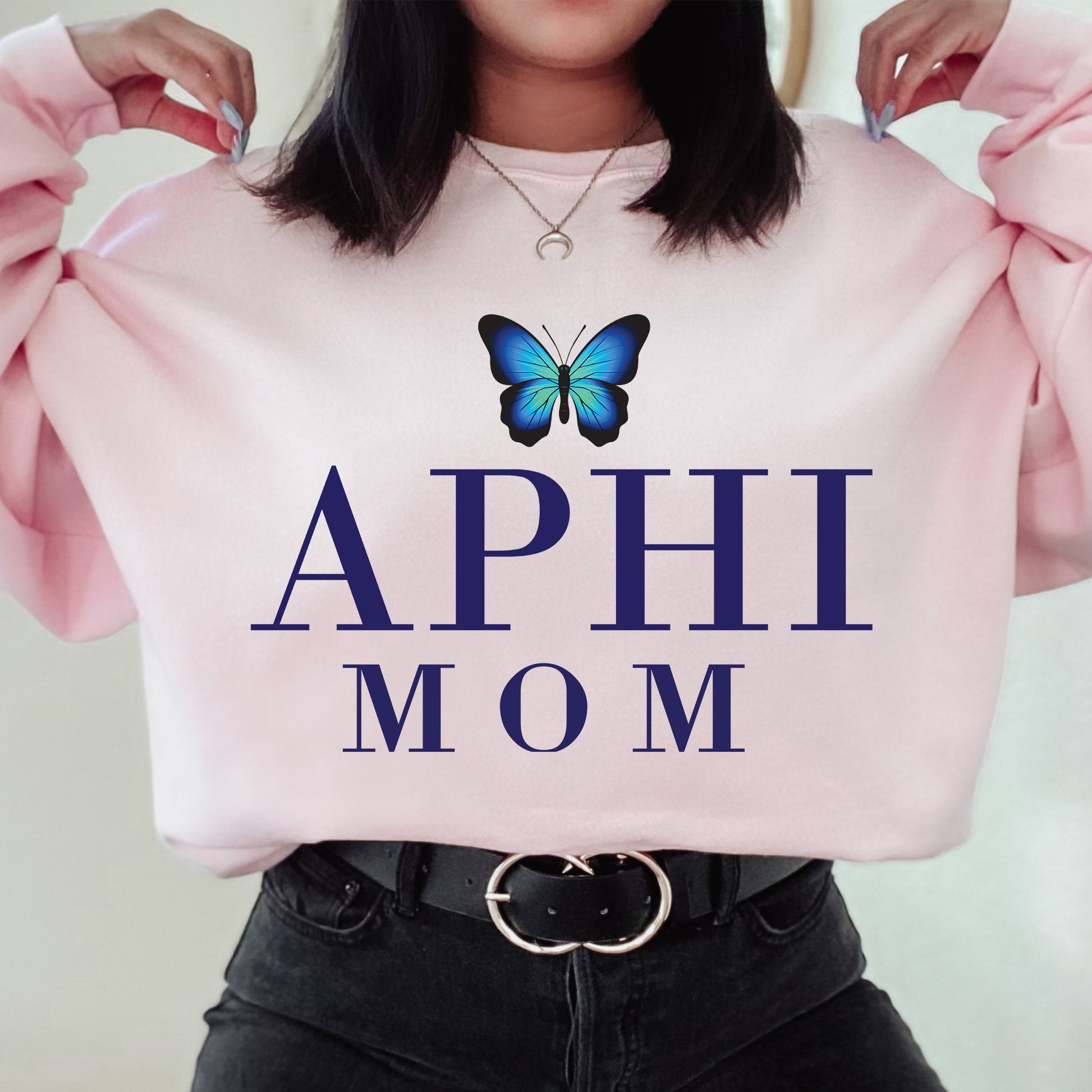 a woman holding a pink sweatshirt with a butterfly on it