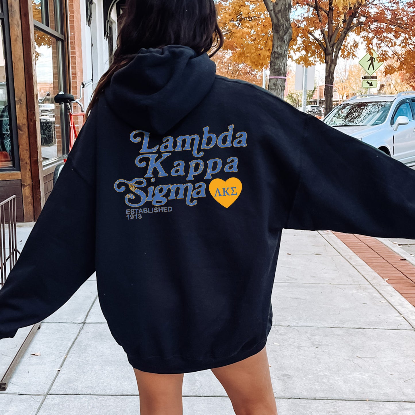 a woman in a black hoodie is walking down the street