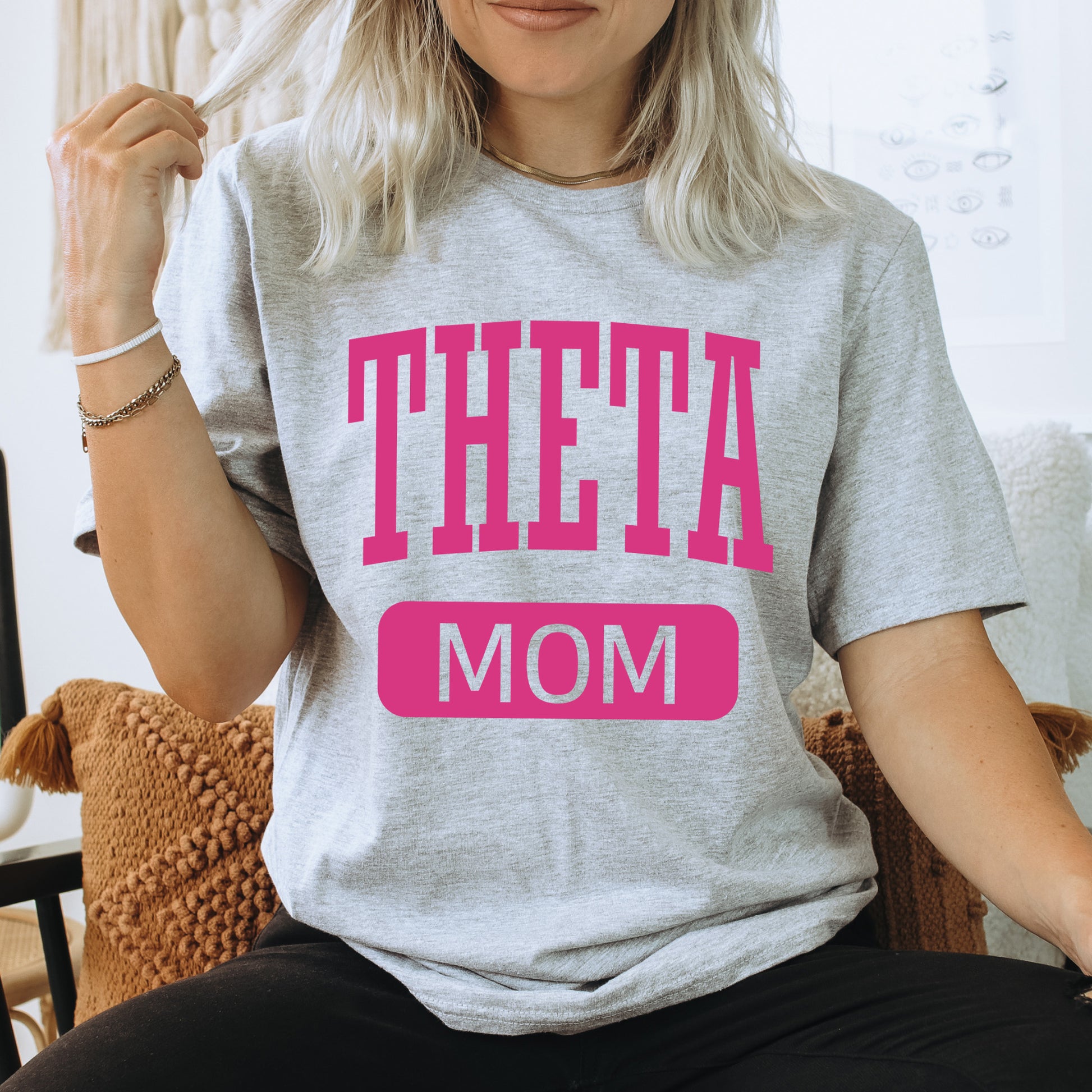 a woman wearing a t - shirt that says theta mom