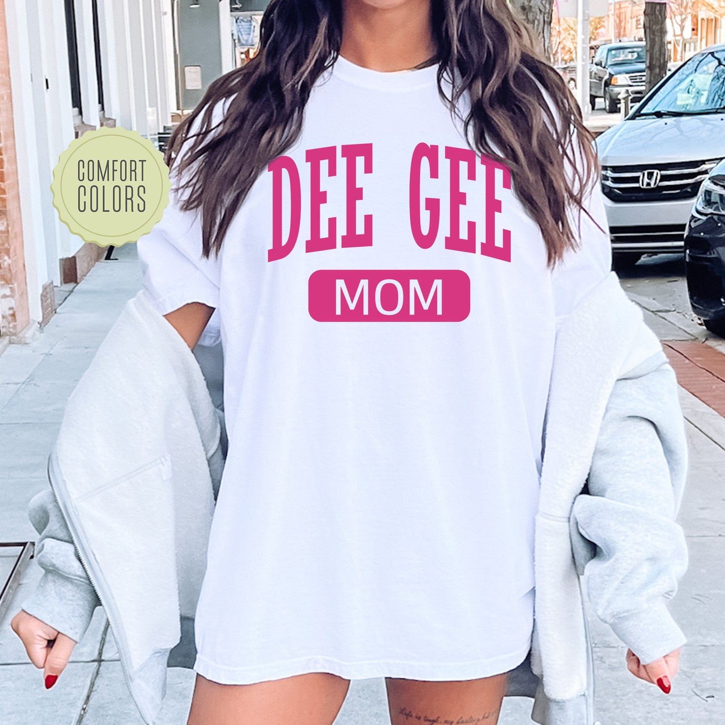 a woman wearing a white tee shirt that says dee gee mom