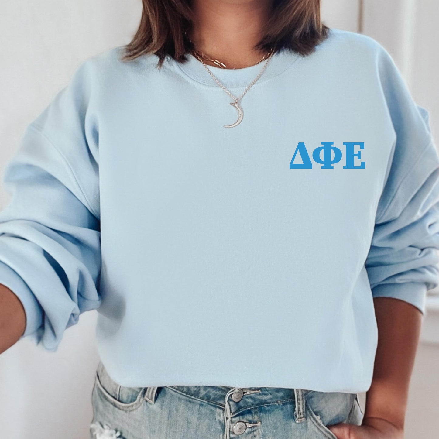a woman wearing a light blue sweatshirt with the letters aoe on it