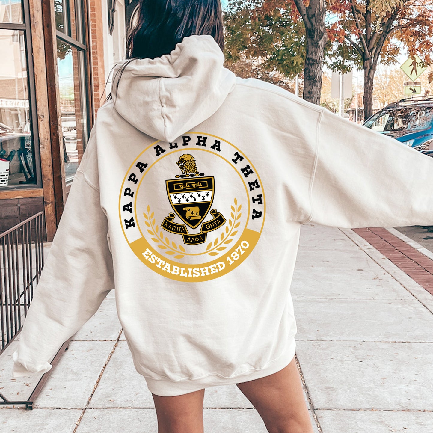 a woman walking down a sidewalk wearing a white hoodie