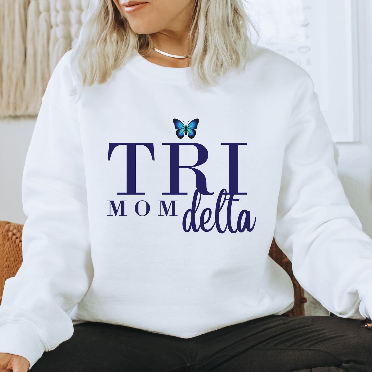 a woman sitting on a chair wearing a sweatshirt that says trii mom delta