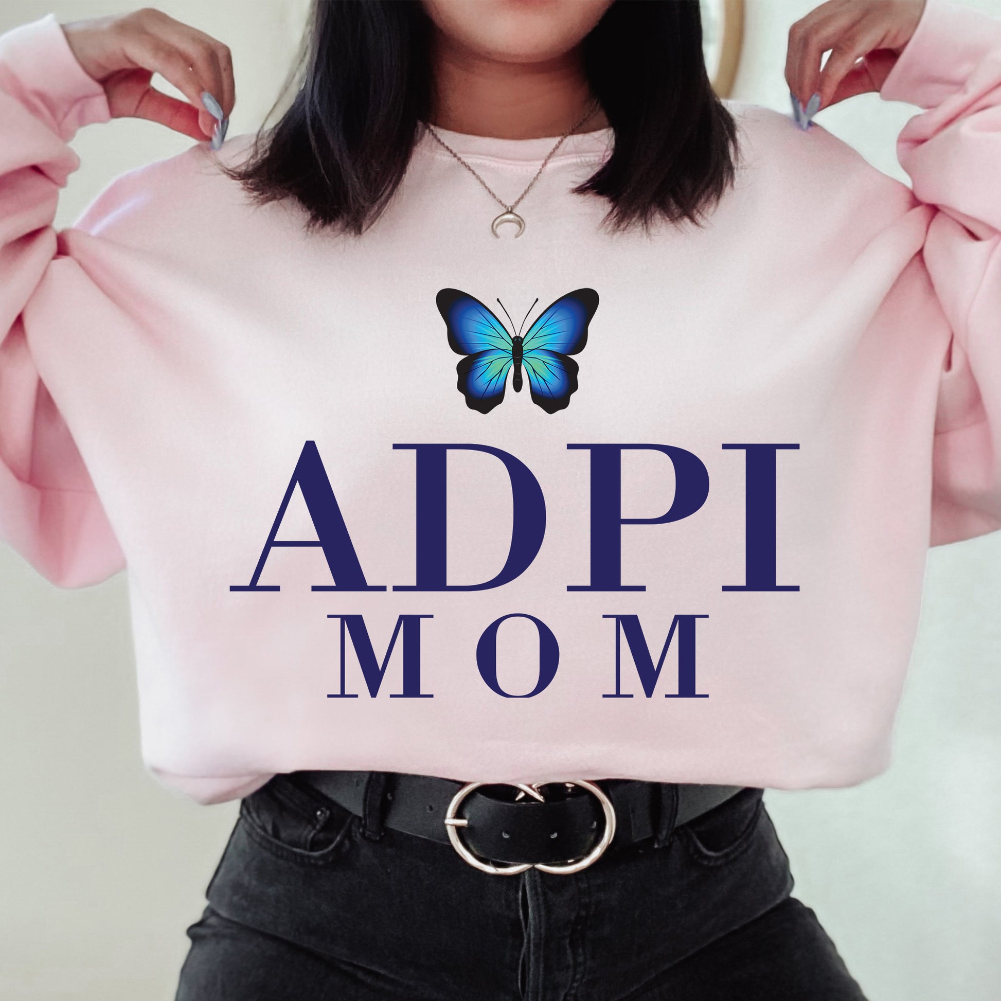 a woman holding a pink sweatshirt with a butterfly on it
