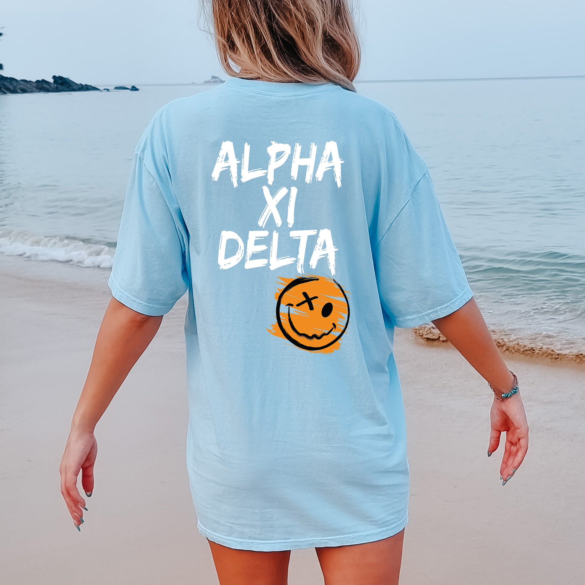 a woman walking on the beach with a smile on her shirt
