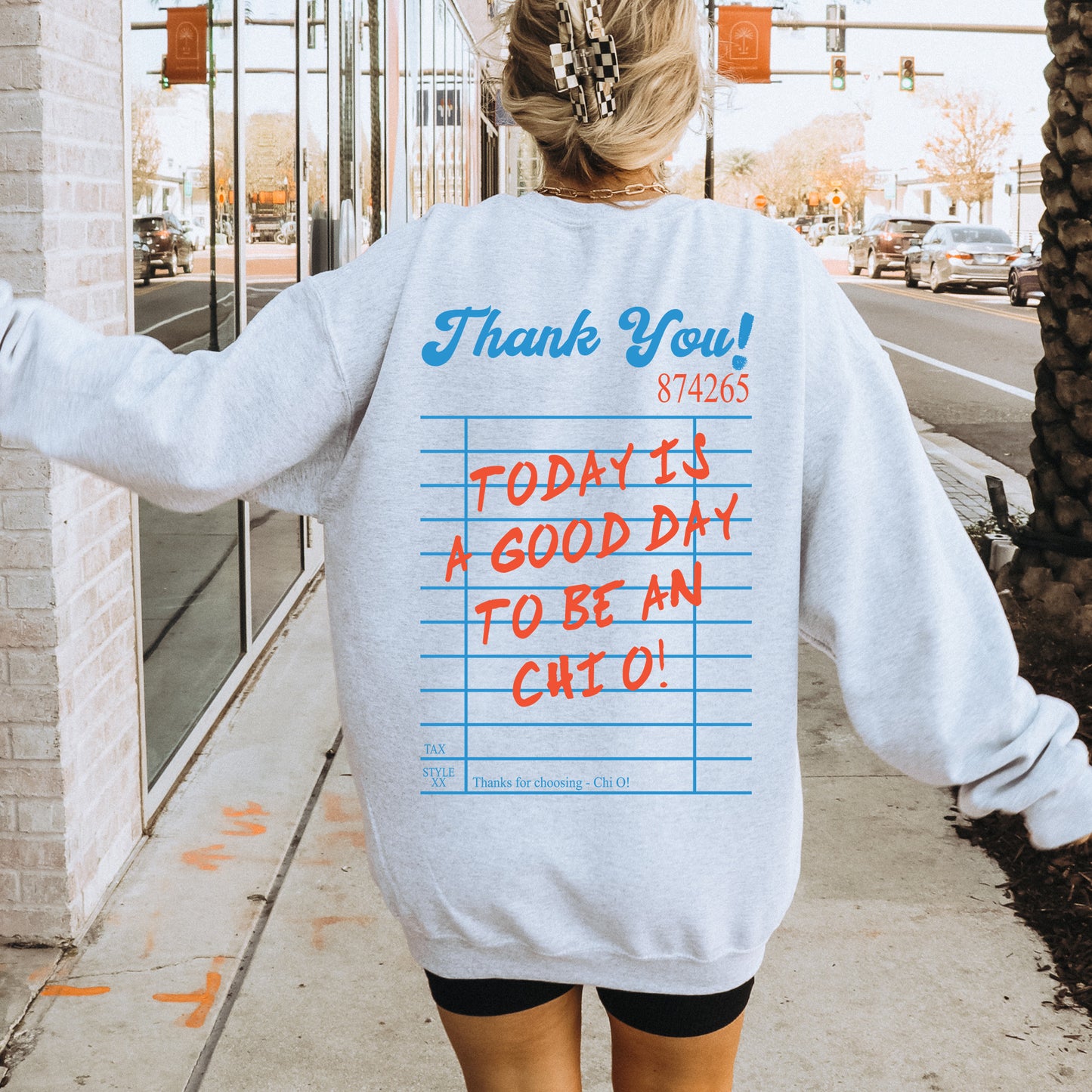 a woman walking down a sidewalk wearing a sweatshirt with writing on it