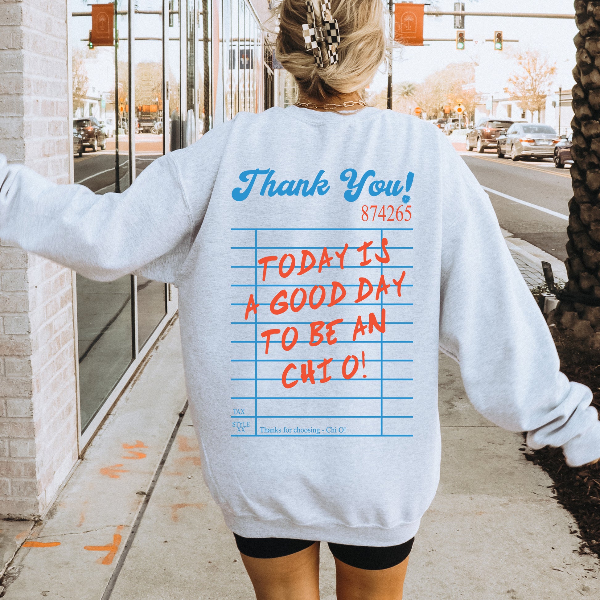 a woman walking down a sidewalk wearing a sweatshirt with writing on it